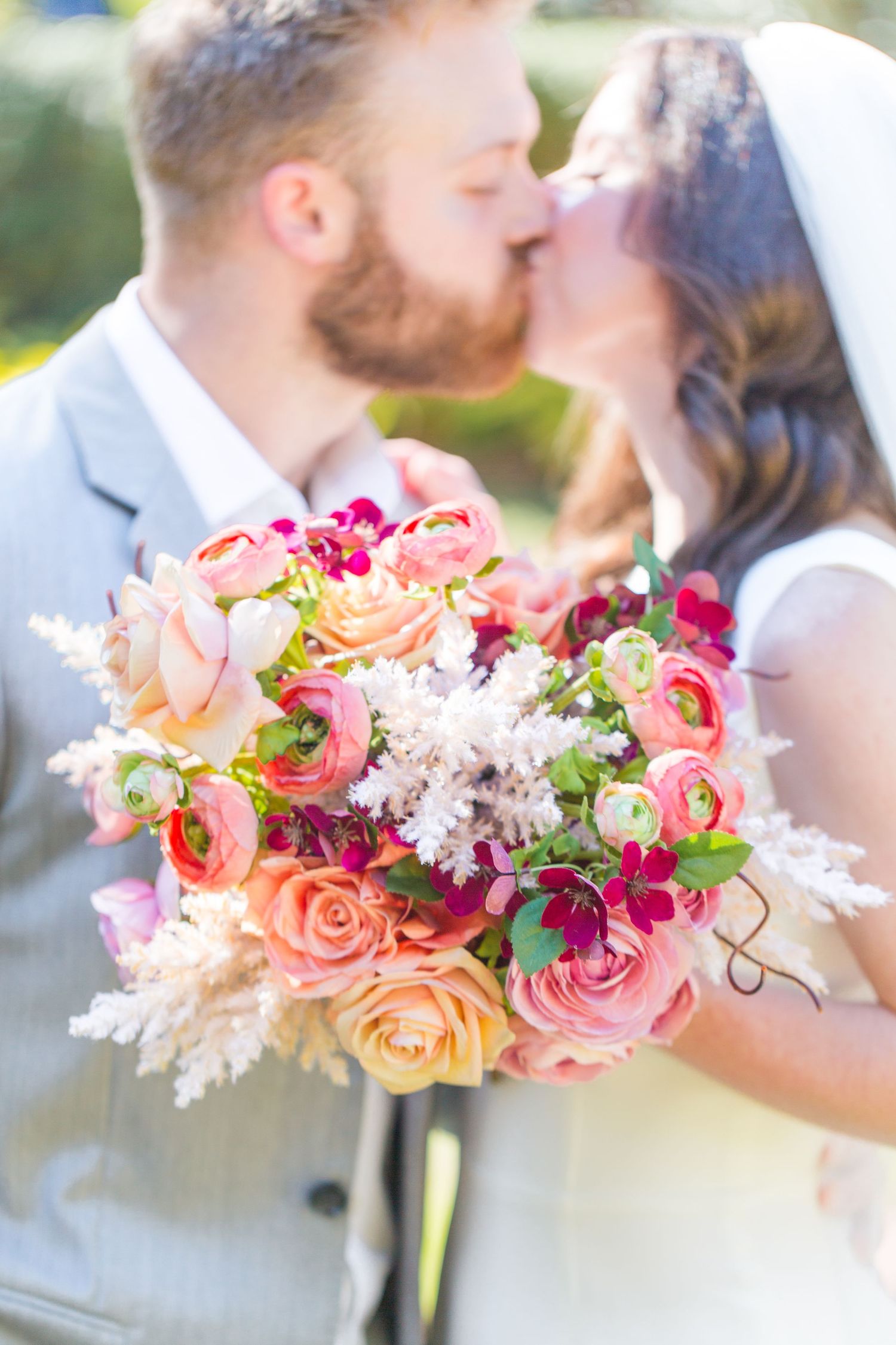 Vibrant coral and pink floral bouquets captured in romantic sunlit detail.