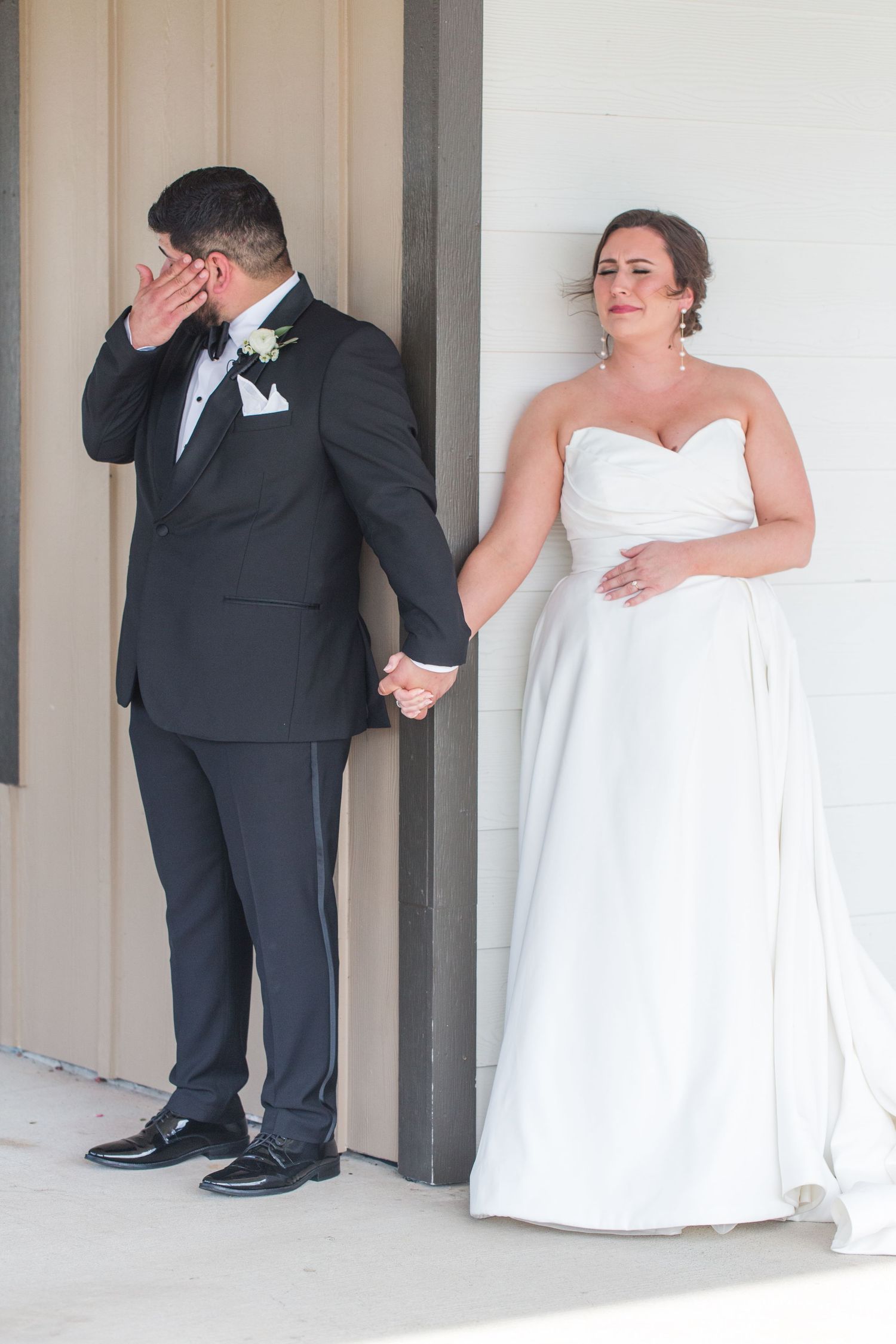 Couple shares emotional reactions while separated by a wall before their wedding ceremony.