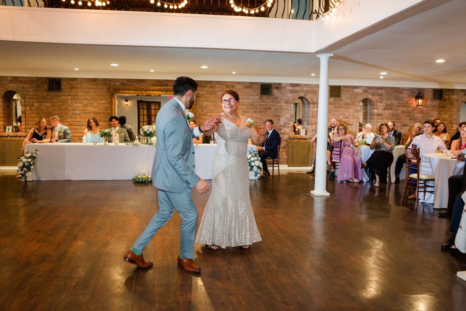 Wedding reception dance sequence in venue with exposed brick walls and white columns.