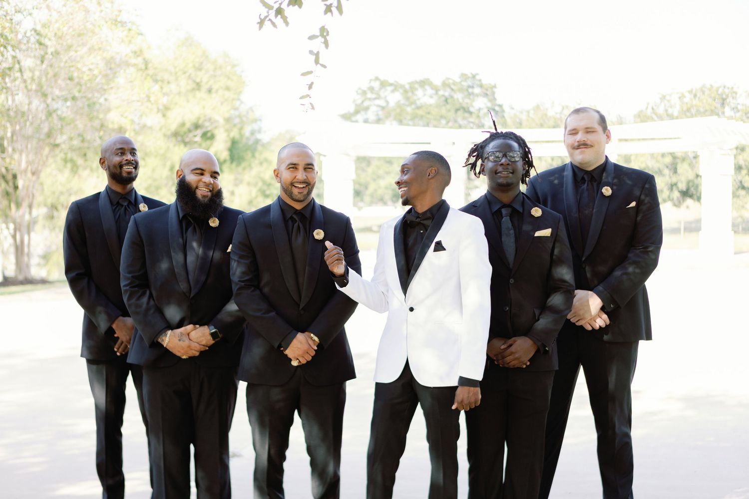 Wedding party in formal black and white attire posing outdoors.