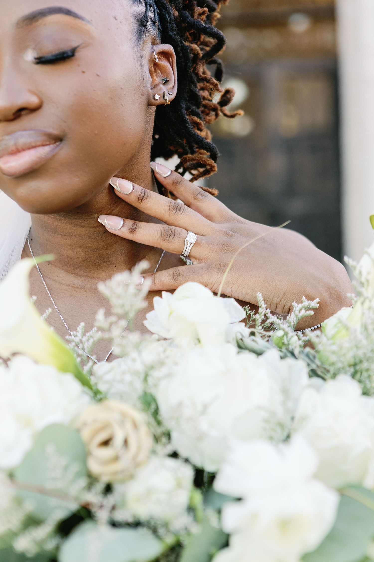 Close-up artistic wedding photos showing elegant bouquet of white flowers and eucalyptus against a blurred background.