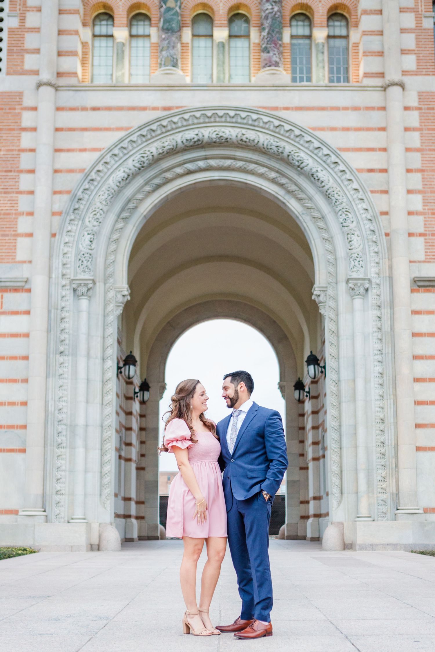 A couple poses together against the beautiful backdrop of a historic university building.