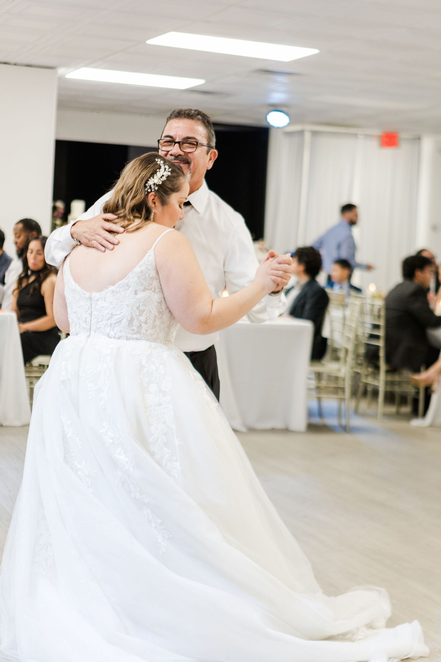 Couples dancing together at a wedding celebration in a spacious white venue.