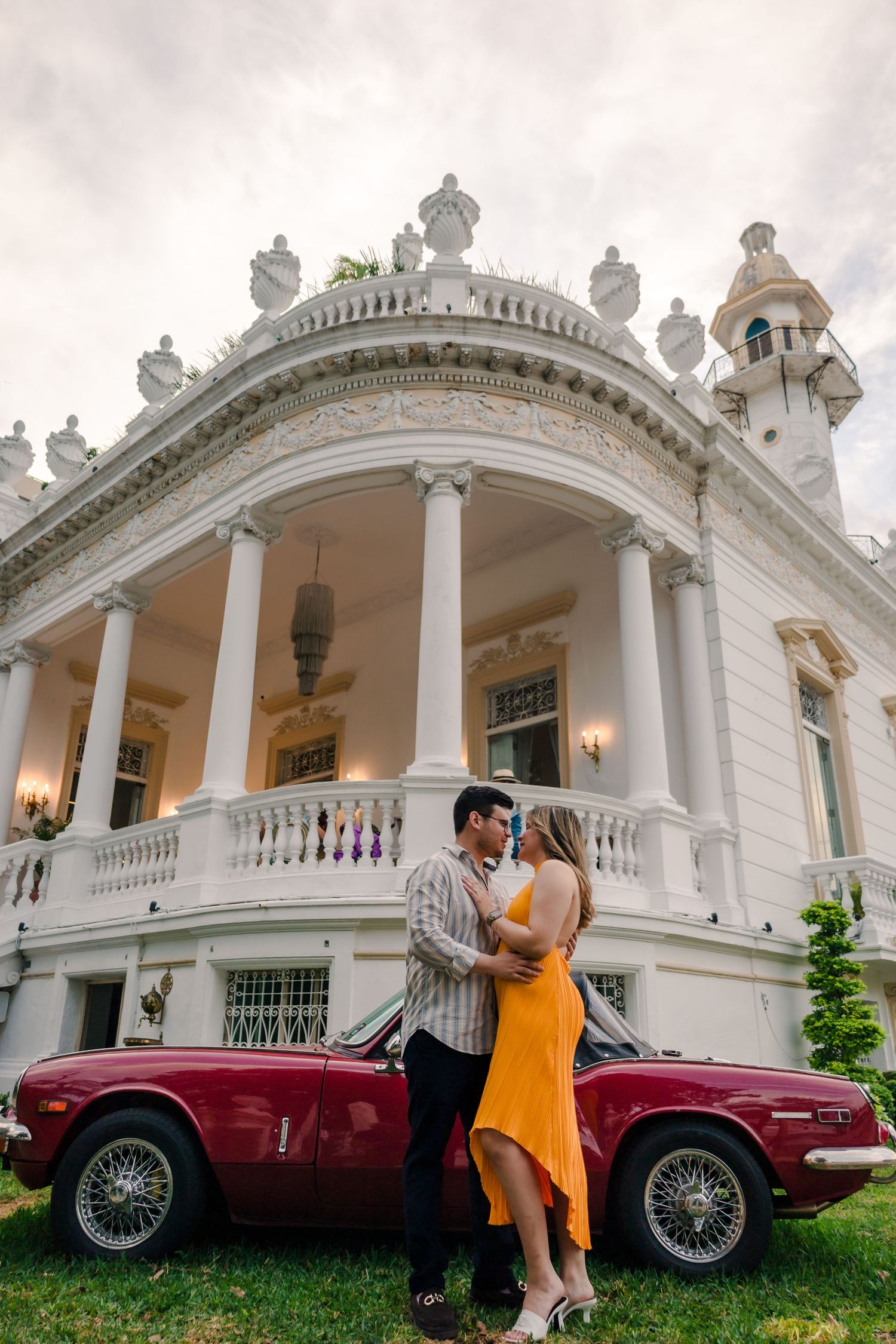 Sesión de pareja frente a una hacienda en Mérida Yucatán con automóvil clásico durante sesión de compromiso