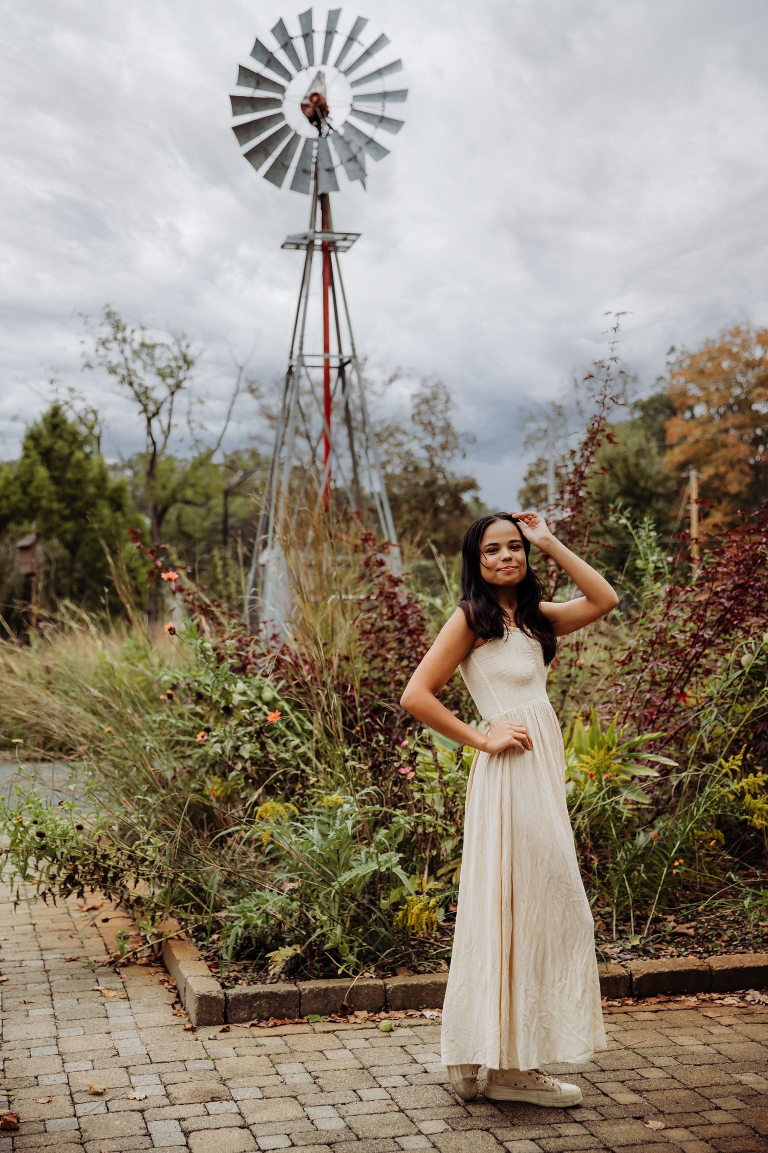 Girl stands in front of windmill at Inniswood Metro Gardens in Westerville Ohio during Senior Portraits with Tami Harris Photography