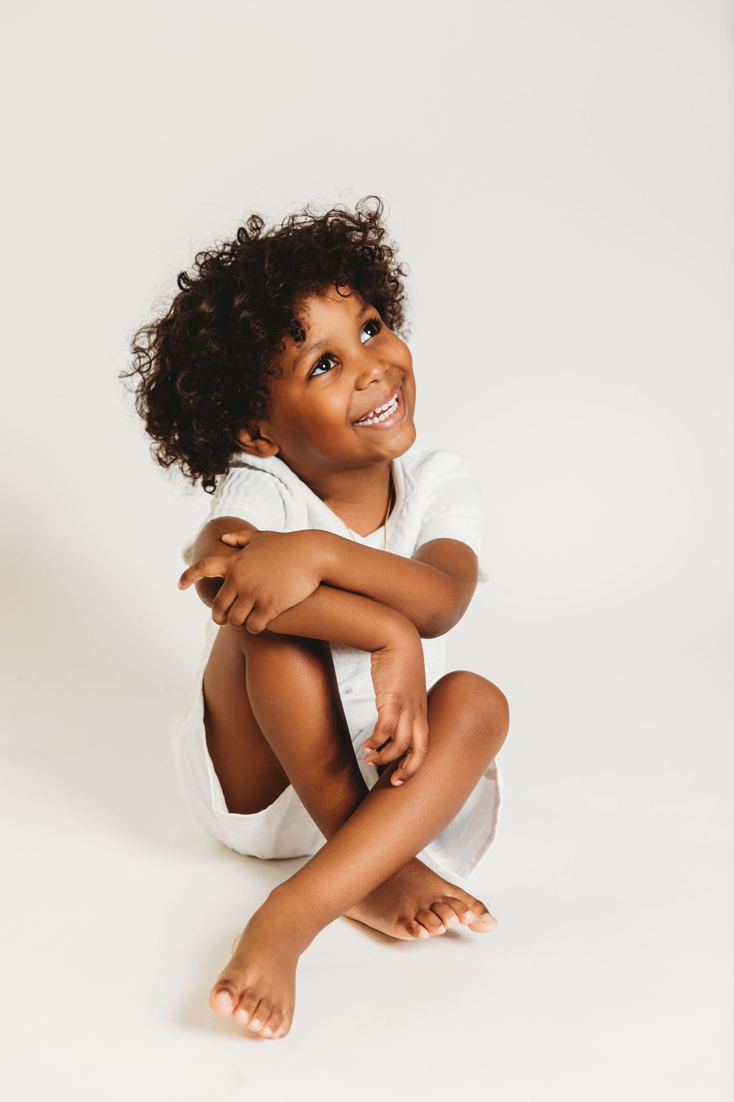 Boy with long curly hair looks up smiling during his 4th birthday photos with Tami Harris Photography in central Ohio studio
