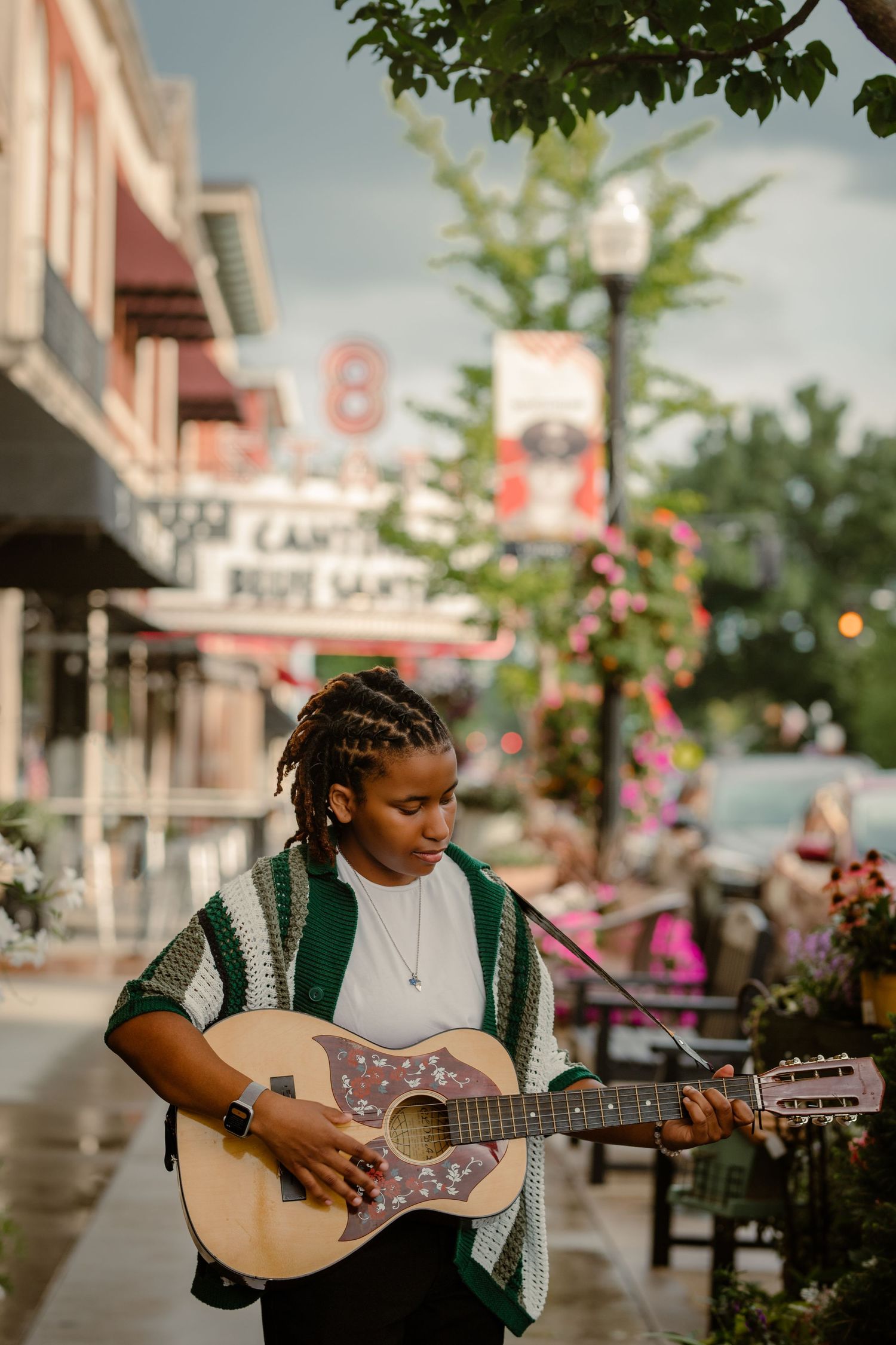 Senior girl with dreadlocks plays guitar in Uptown Westerville during senior portrait photoshoot with Tami Harris Photography