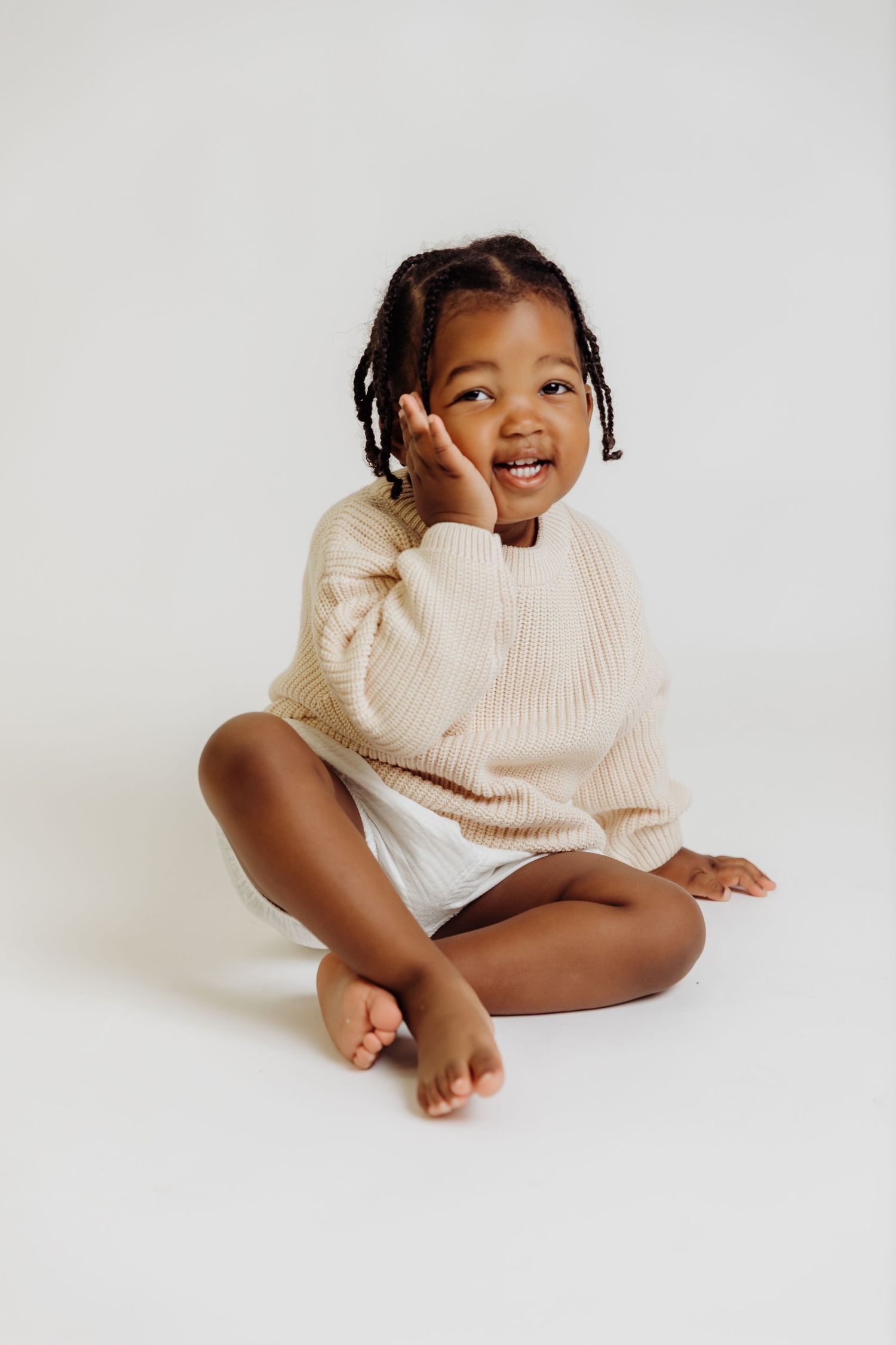 Little boy smiles with hand on his cheek during 2nd birthday photoshoot with Tami Harris Photography in Worthington studio