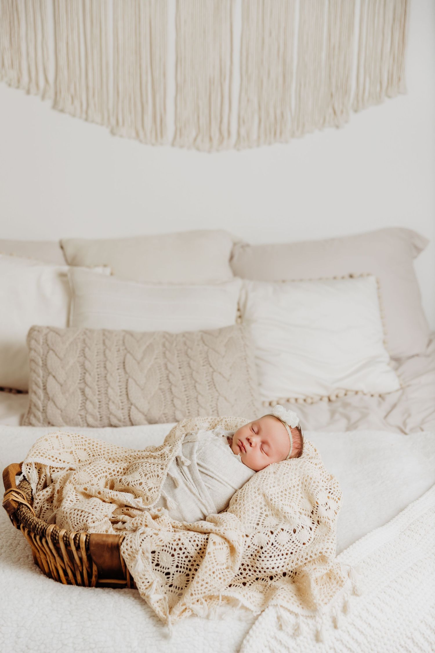 Newborn baby girl sleeps peacefully in basked placed on a bed in Tami Harris Photography studio in Worthington, Ohio