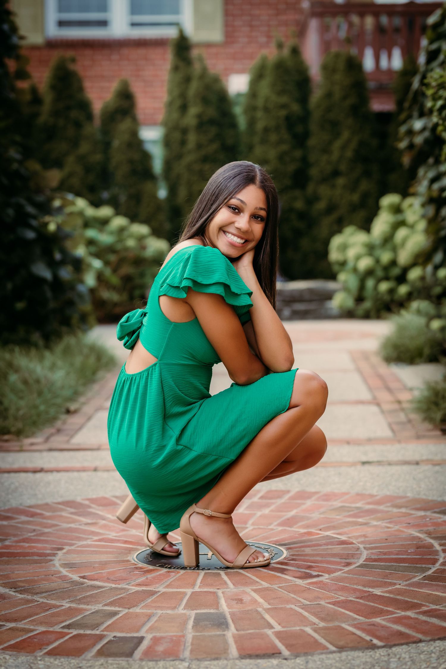 Senior girl crouched down in church courtyard in German Village in Columbus, OH for photoshoot with Tami Harris Photography