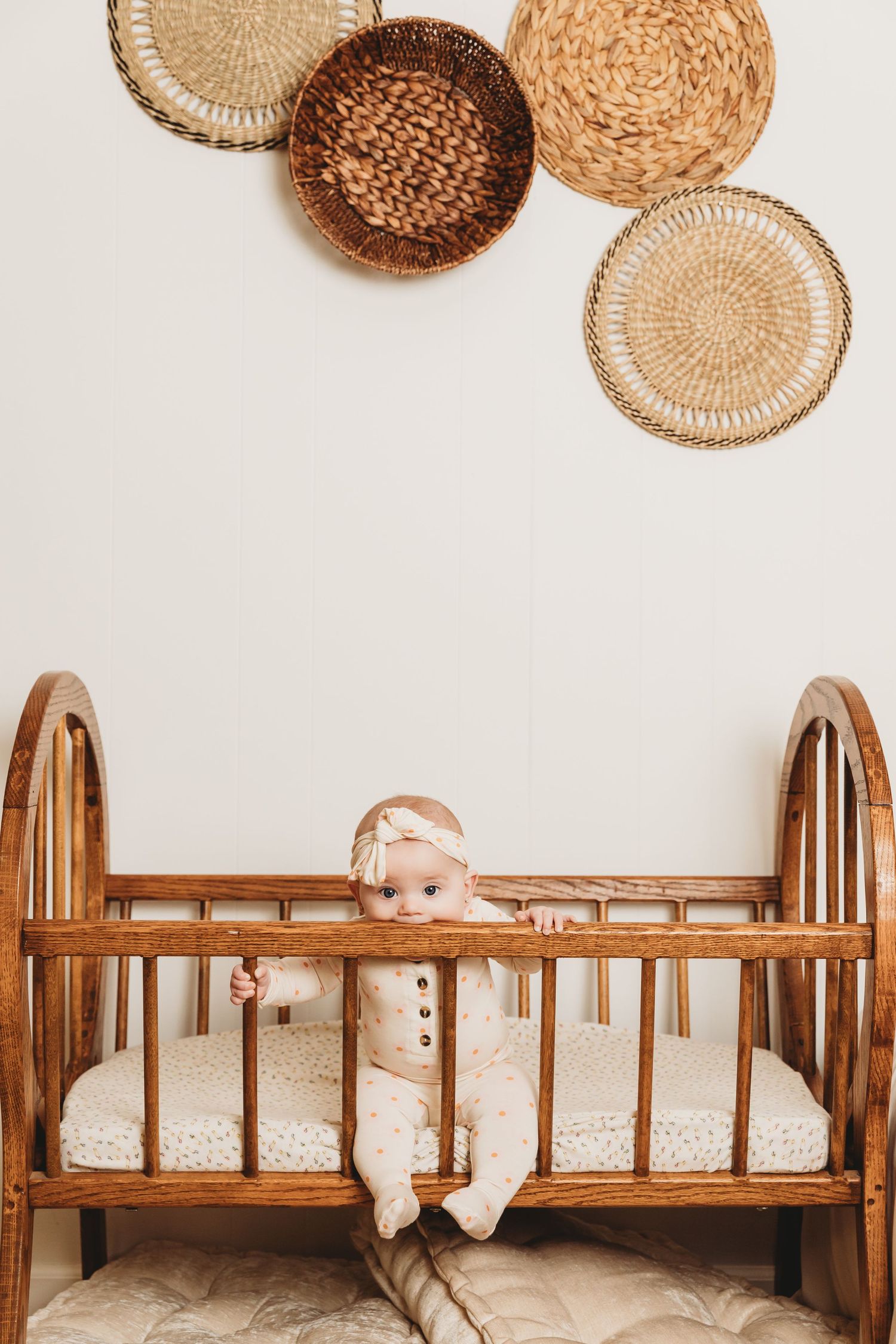 Teething baby girl bites wooden crib during 6-month baby milestone portrait session with Tami Harris Photography in Columbus Oh studio