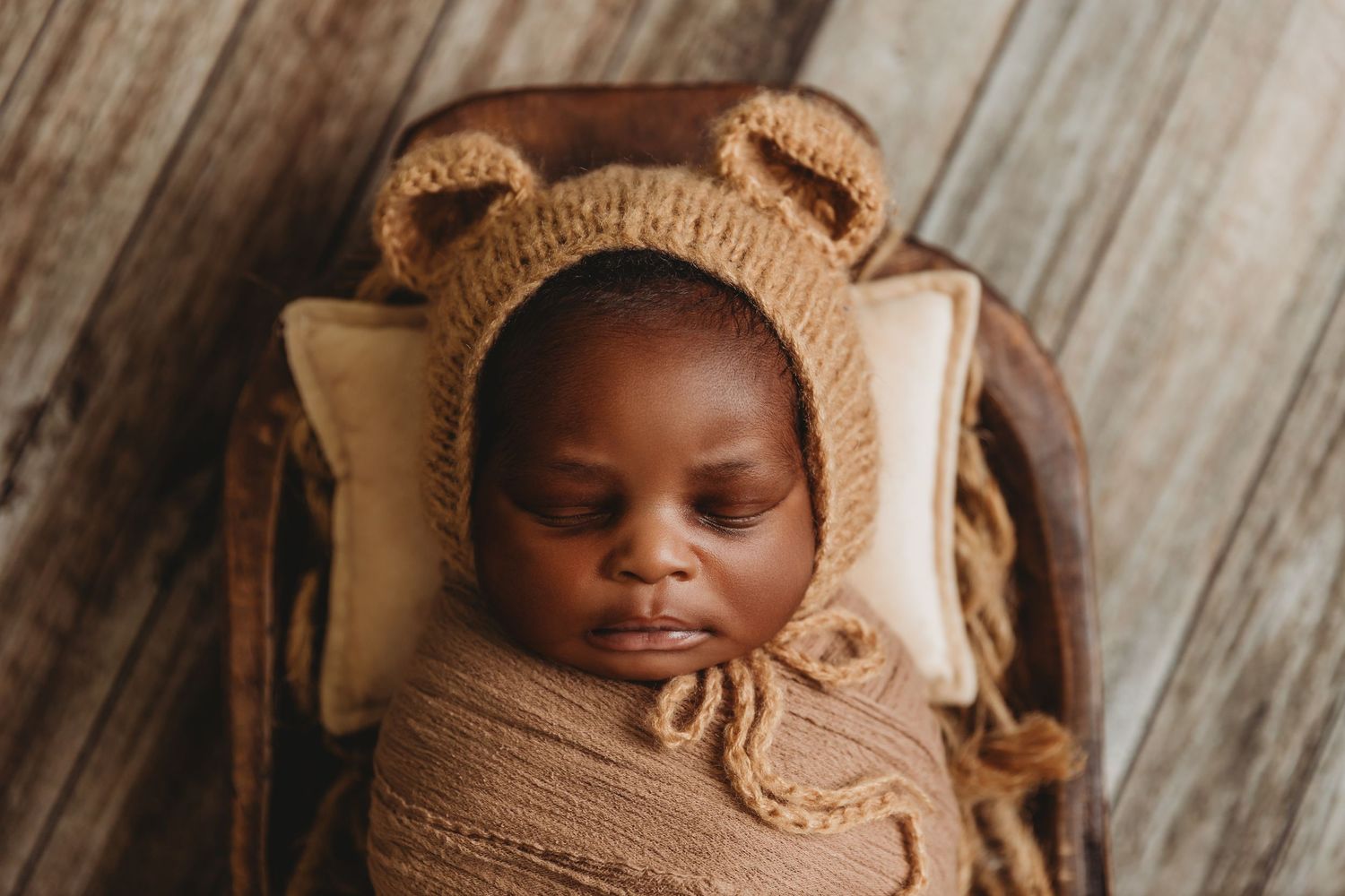 newborn baby boy sleeps in wooded prop with teddy bear ears hat during photos with Tami Harris Photography in central Ohio studio