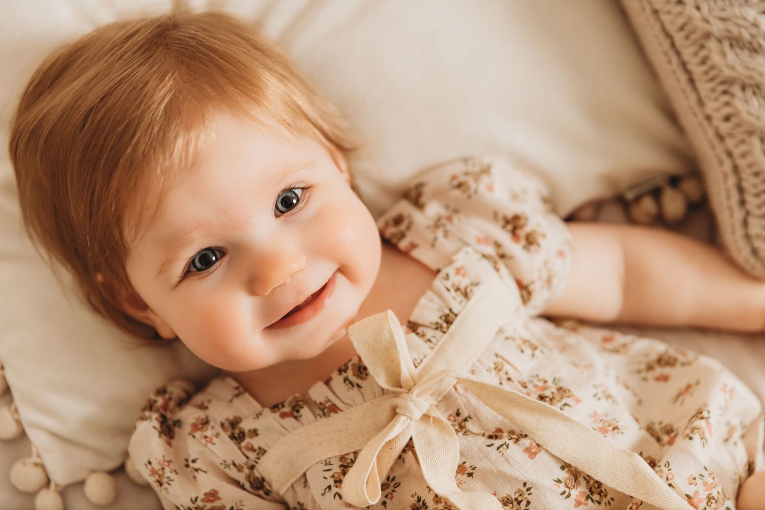 Baby girl smiling while laying on studio bed at Tami Harris Photography in Worthington, Ohio for first birthday photoshoot