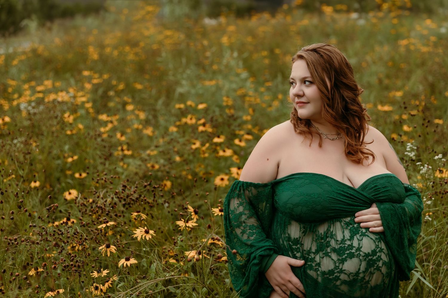 Pregnant woman holds belly while standing in wildflowers in New Albany Ohio for on-location Maternity photos with Tami Harris Photography