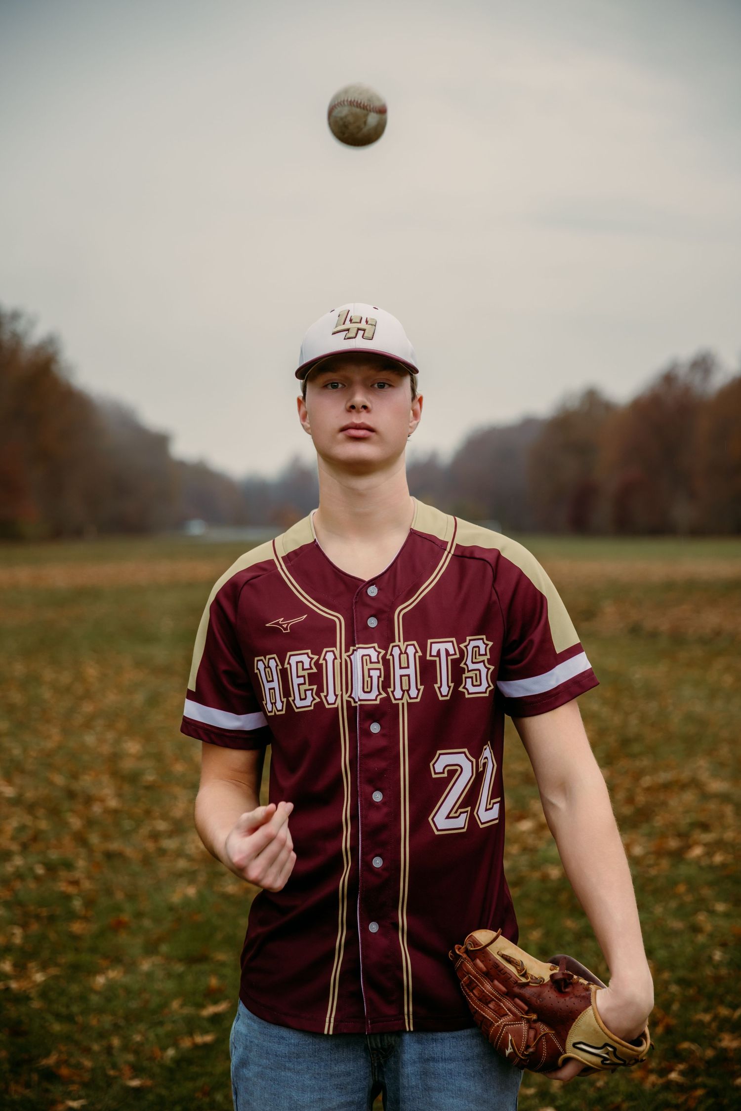 Senior Guy throws baseball in the air while standing in field in Westerville Oh for Senior portrait session with Tami Harris Photography