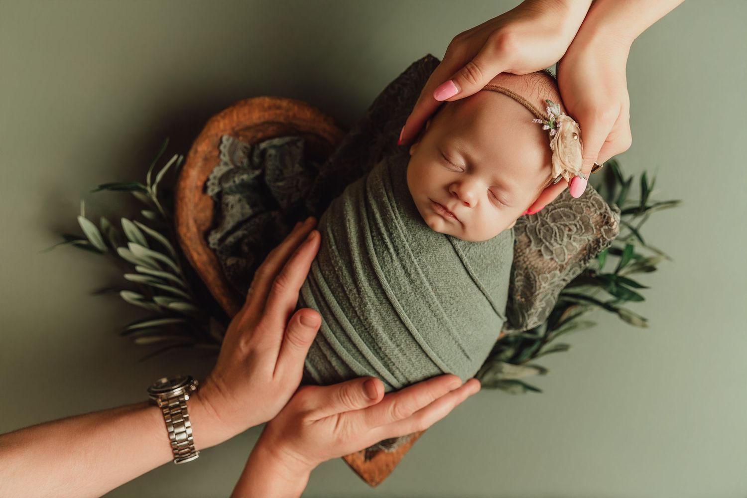 Newborn parent support baby girl in hands while she is wrapped and placed in heart-shaped bowl in Tami Harris Photography studios