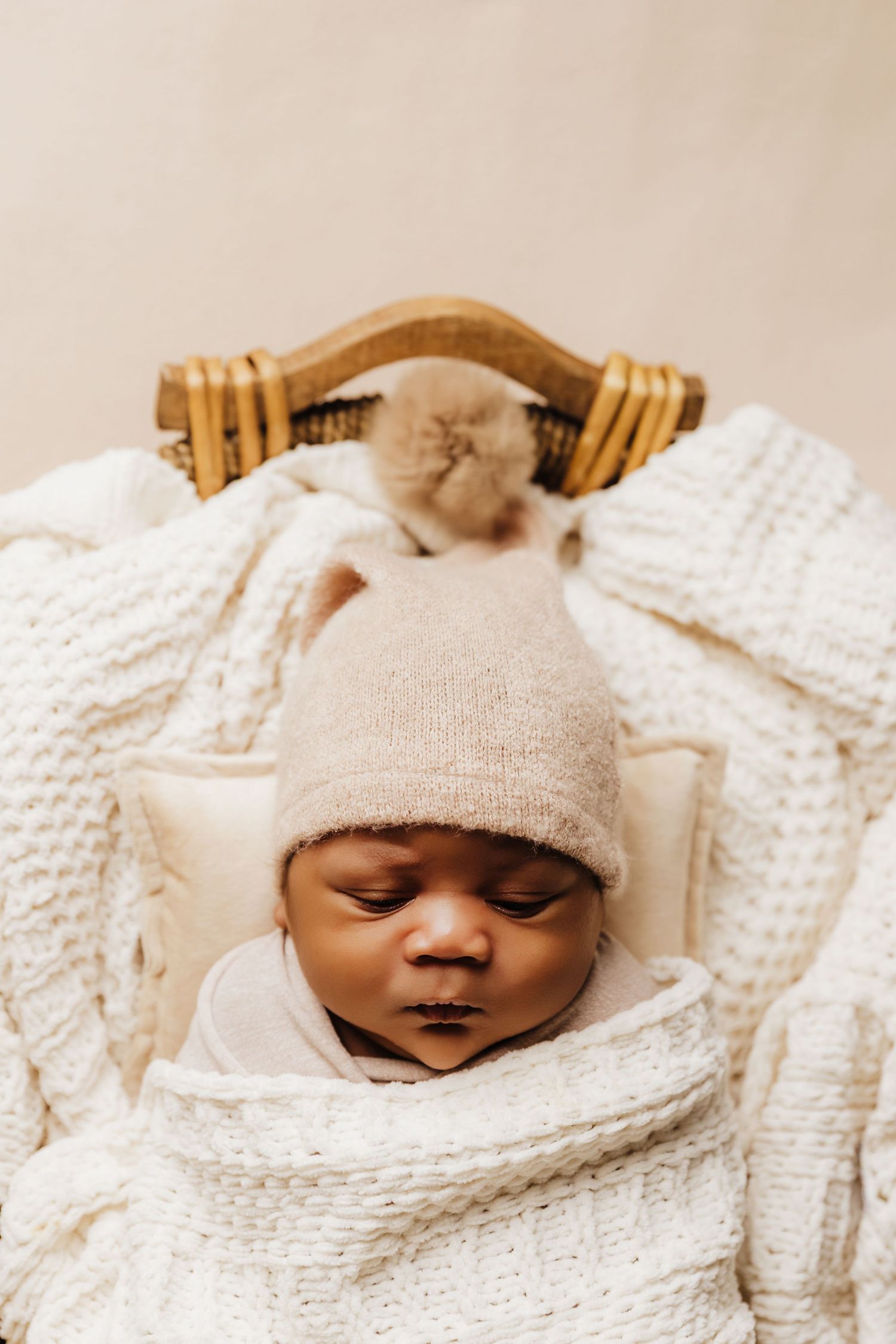 Baby boy wrapped in cream swaddling sleeping in a basket during newborn photos with Tami Harris Photography in Worthington, OH studio
