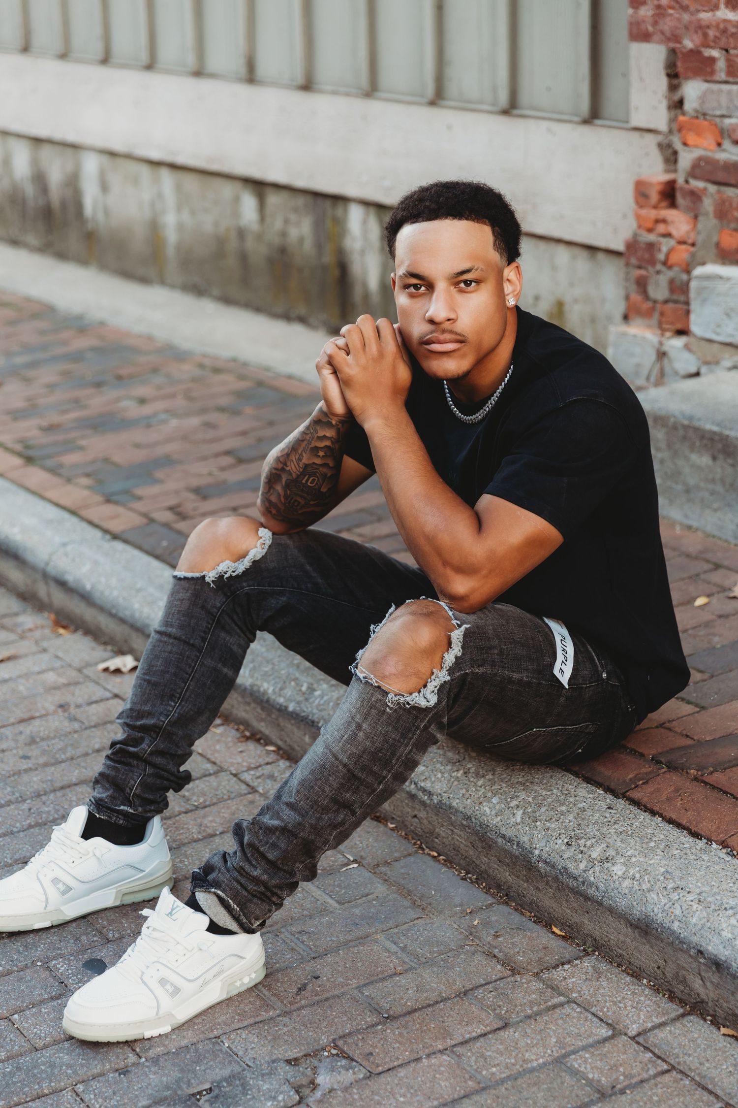 UK Football player Preston Bowman sits relaxing on curb in Uptown Westerville Oh for Senior portraits with Tami Harris Photography