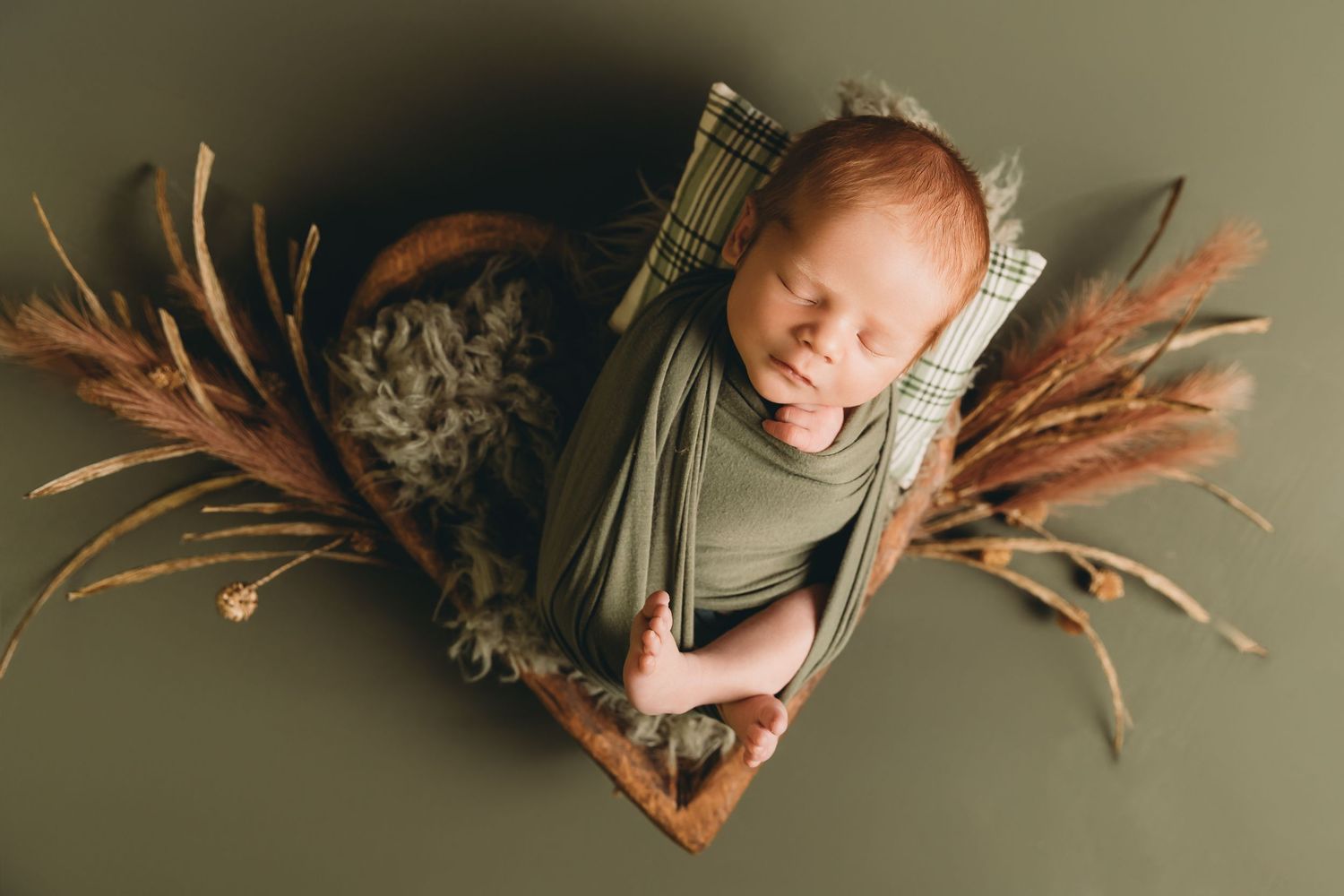 Sleeping newborn baby boy in heart-shaped bowl surrounded by dried brown florals for photoshoot with Tami Harris Photography in Ohio