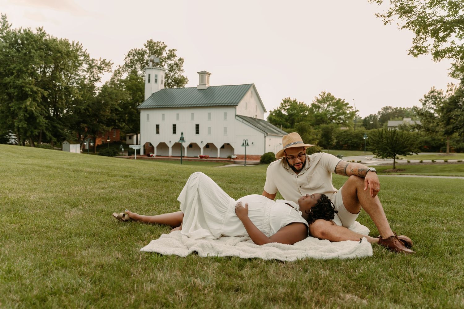 Couple lays on a blanket in the grass at Everal Barn in Westerville Ohio for Maternity photoshoot with Tami Harris Photography