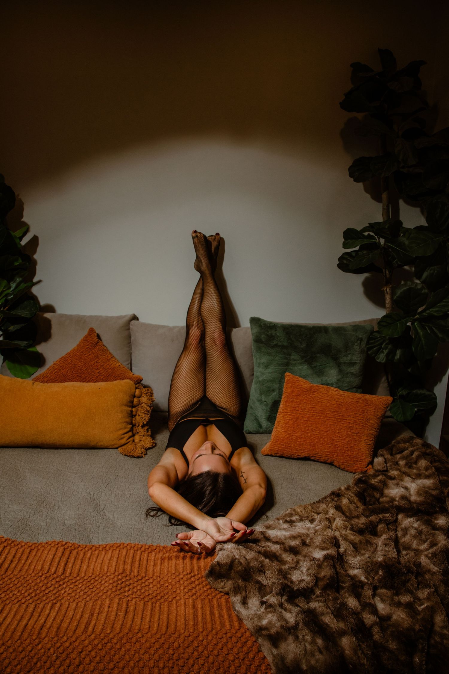 Woman in lingerie lays on bed with arms and legs crossed posed for boudoir photo session with Tami Harris Photography