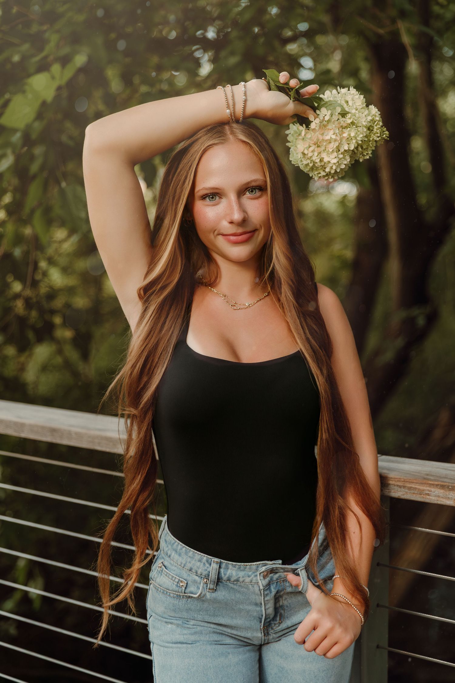Girl stands on a bridge holding bouquet of flowers at Rose Run Park in New Albany Oh for Senior portrait session w/ Tami Harris Photography