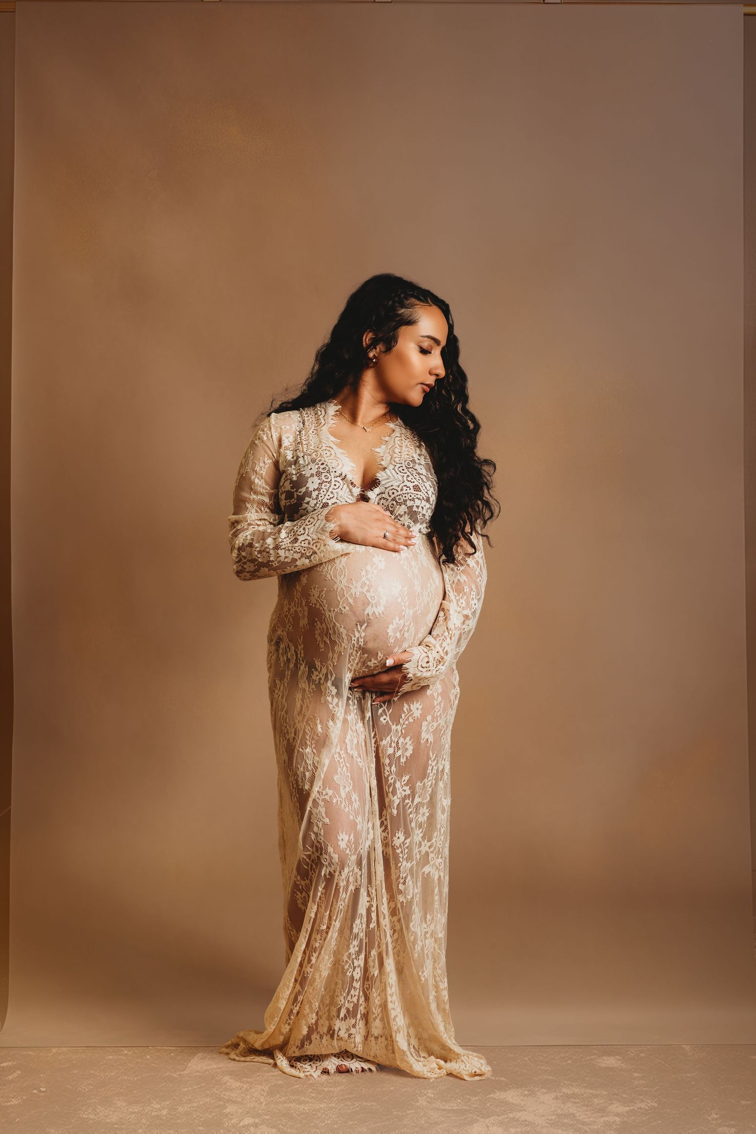 Pregnant mother looks to the side and embraces belly during maternity photoshoot with Tami Harris Photography