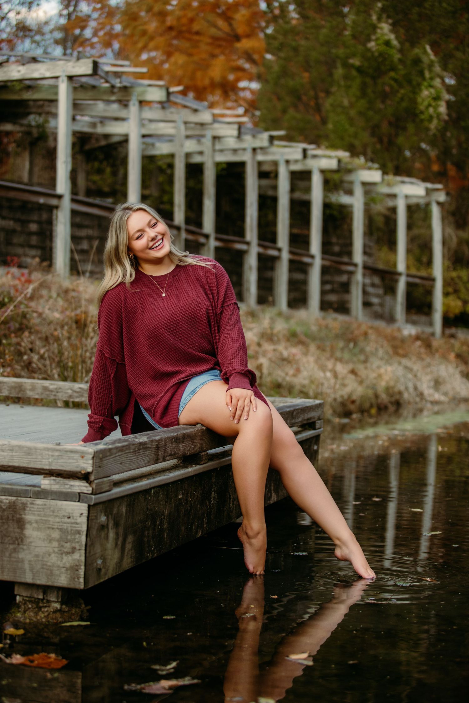 Senior portrait photo session at Inniswoods Metropark in Westerville Ohio where girl sits barefoot with toes in the water in small creek