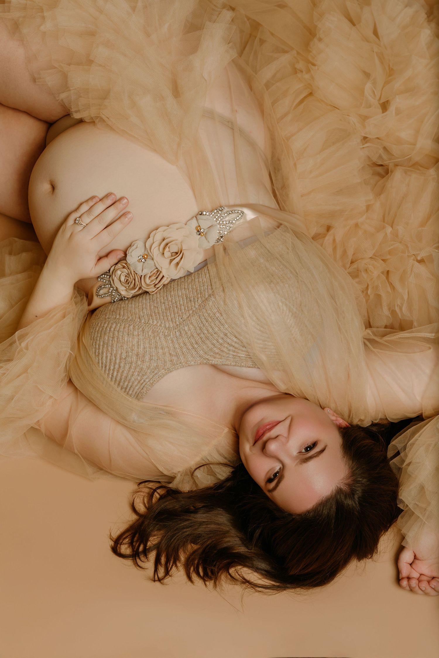 Pregnant mom-to-be lies on the ground in beautiful tulle gown during Maternity photoshoot portraits with Tami Harris Photography