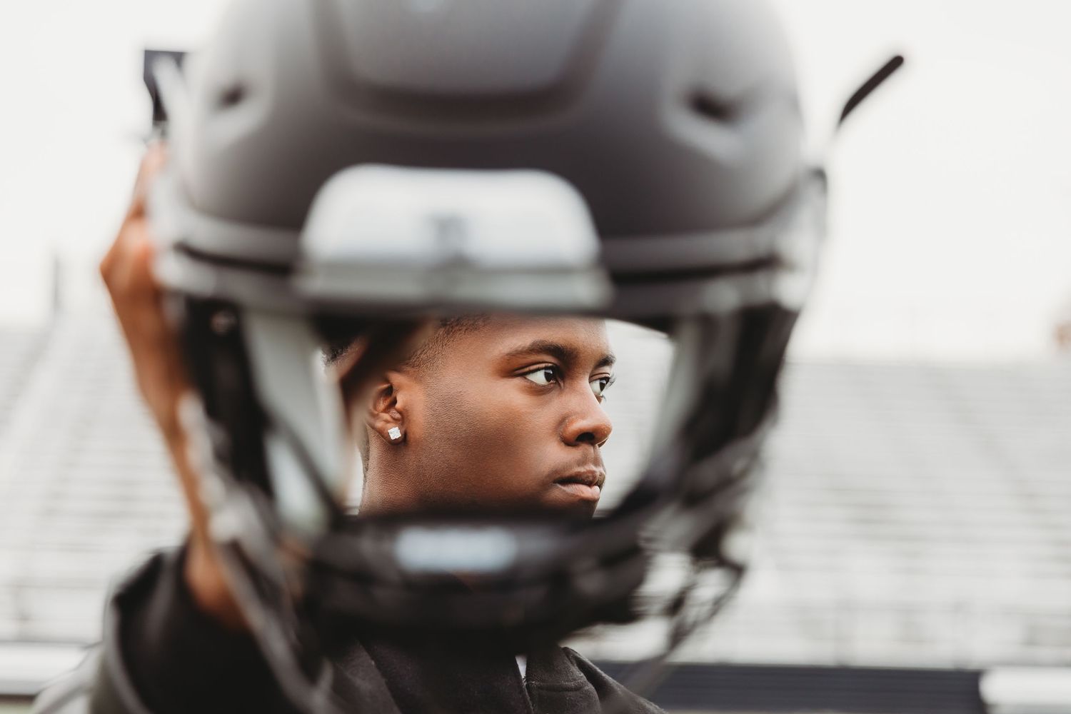 Westerville Central Football player holds helmet during Senior portrait photoshoot with Tami Harris Photography
