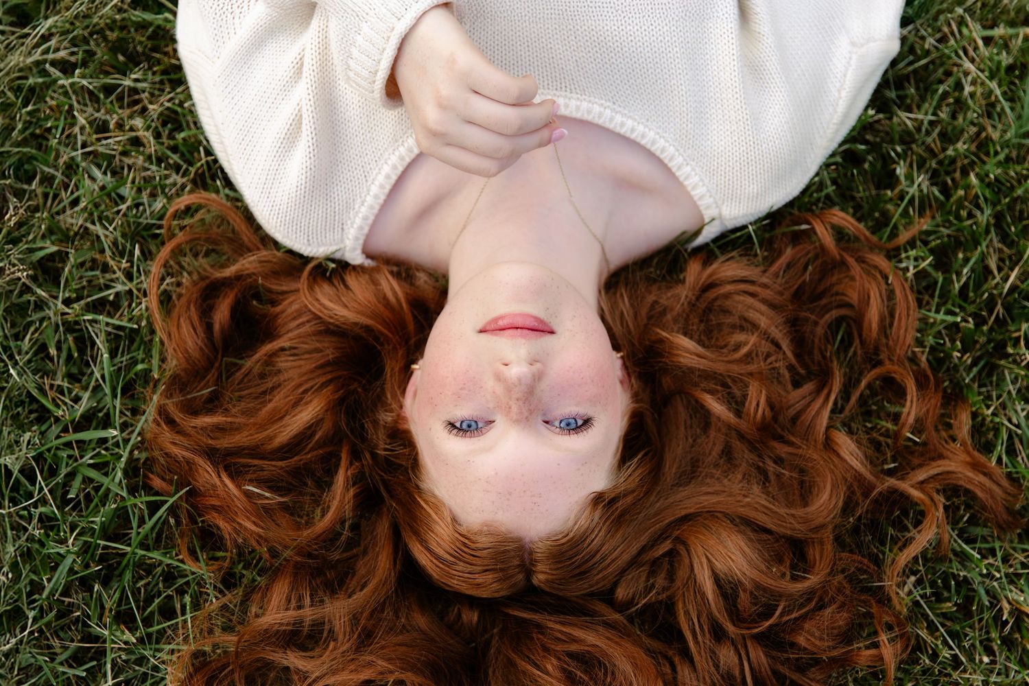 Overhead image of girl with red hair lying in the grass during senior portrait session with Tami Harris Photography