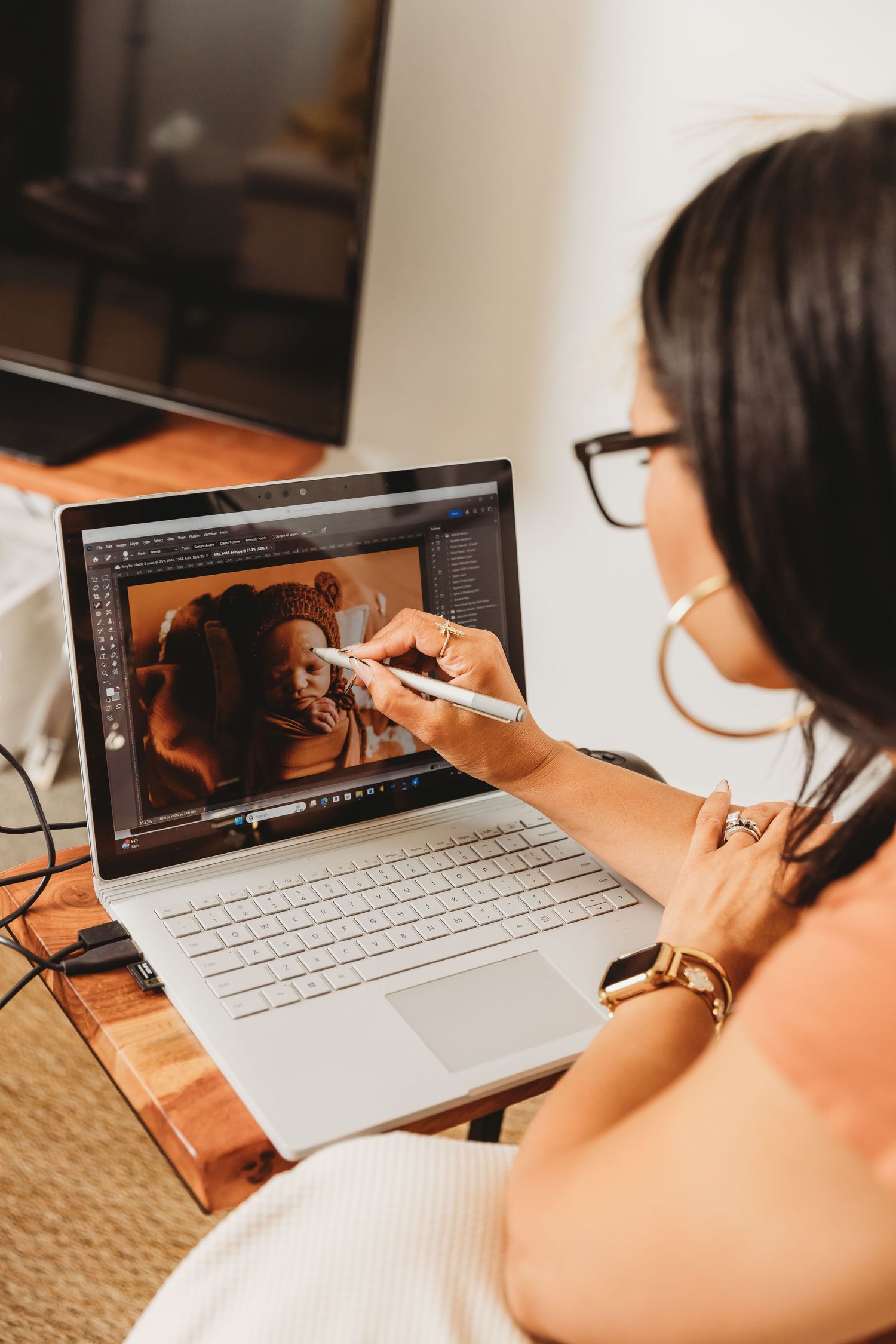Columbus OH Photographer Tami Harris sits at computer editing images from a newborn portrait session in her Worthington studio