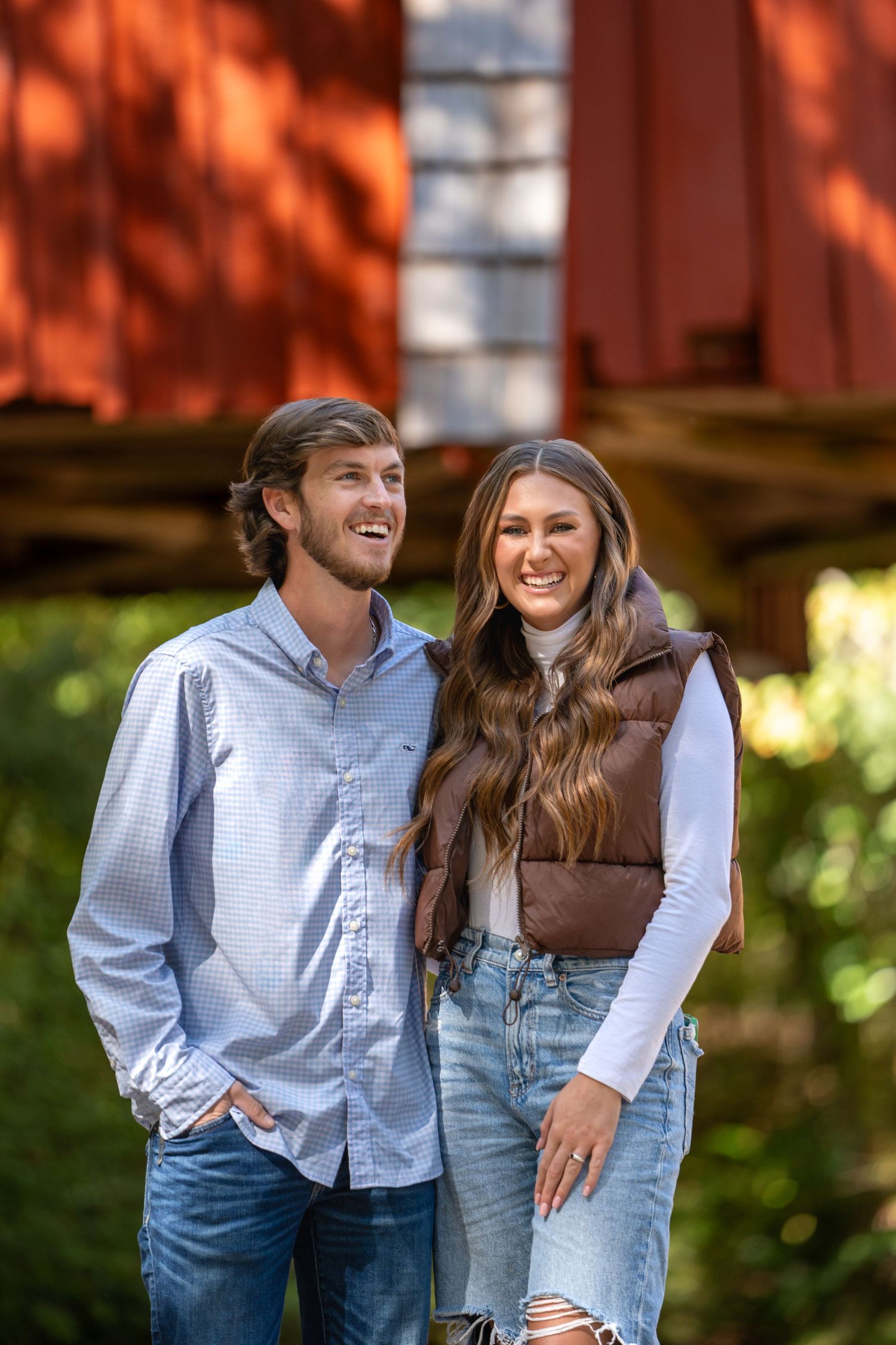 Couple wearing matching blue denim outfits pose casually together outdoors in autumn light.