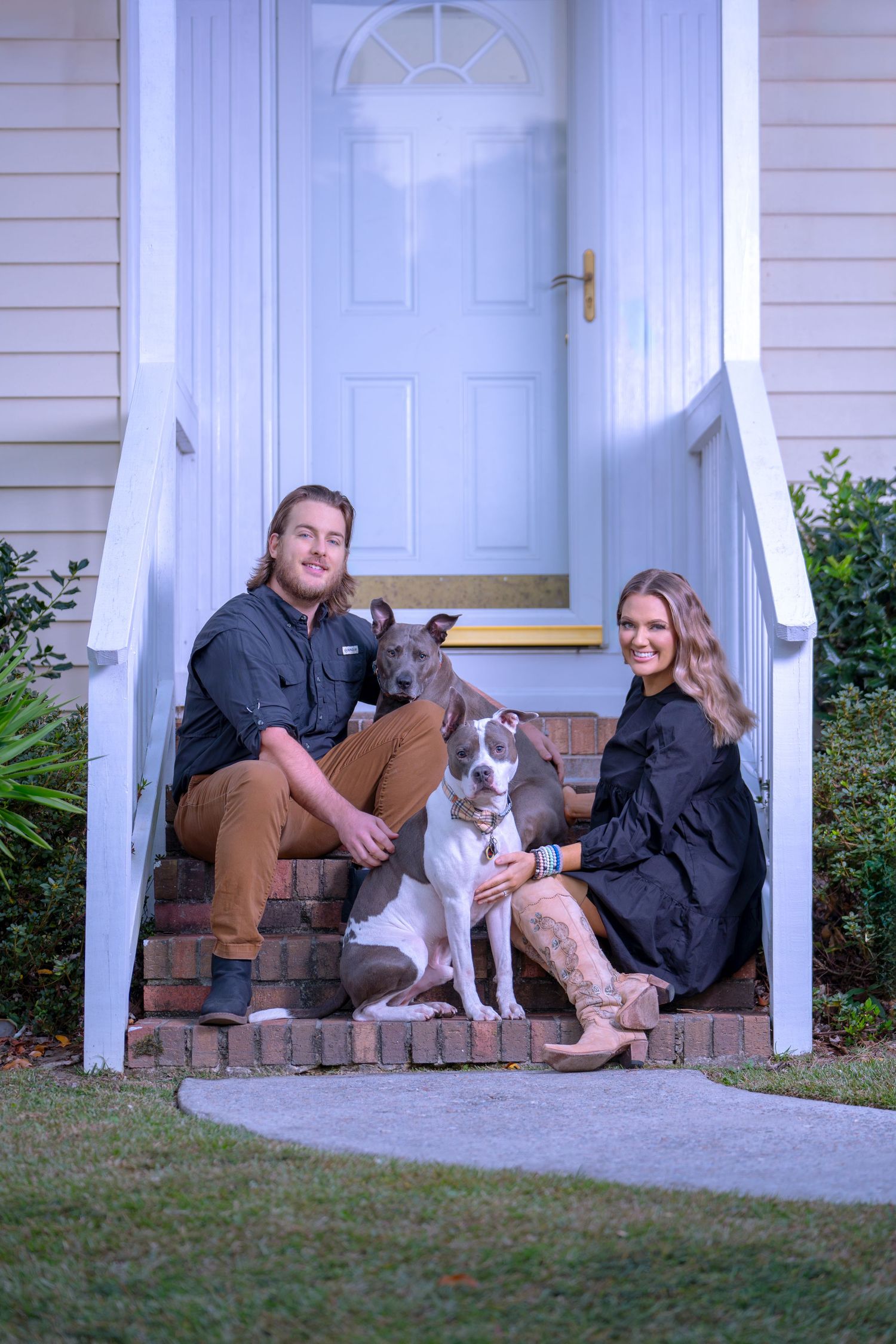 Relaxed family portrait on front porch steps with their dog.