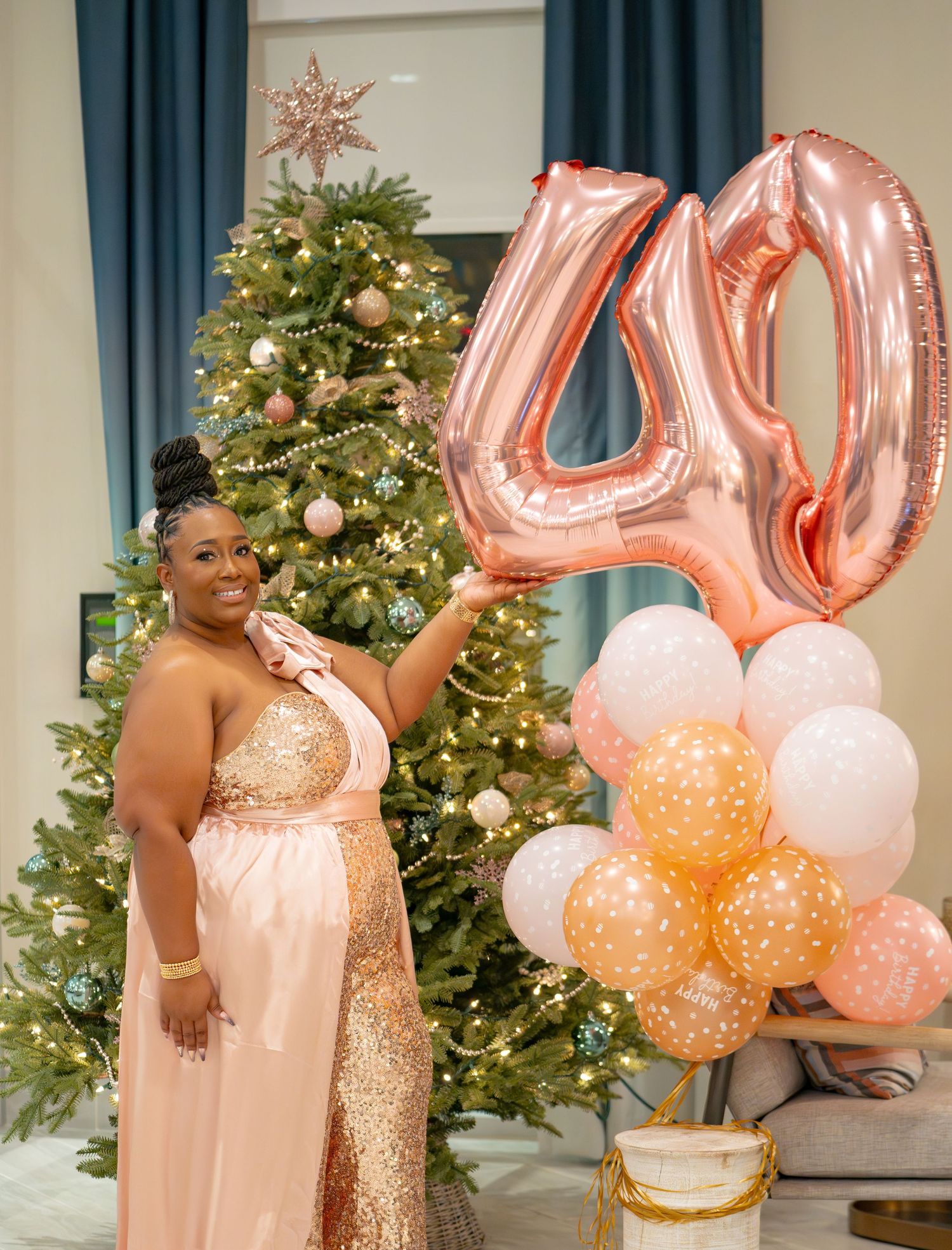 Festive holiday photoshoot setup with Christmas trees, rose gold balloons and peach decor.
