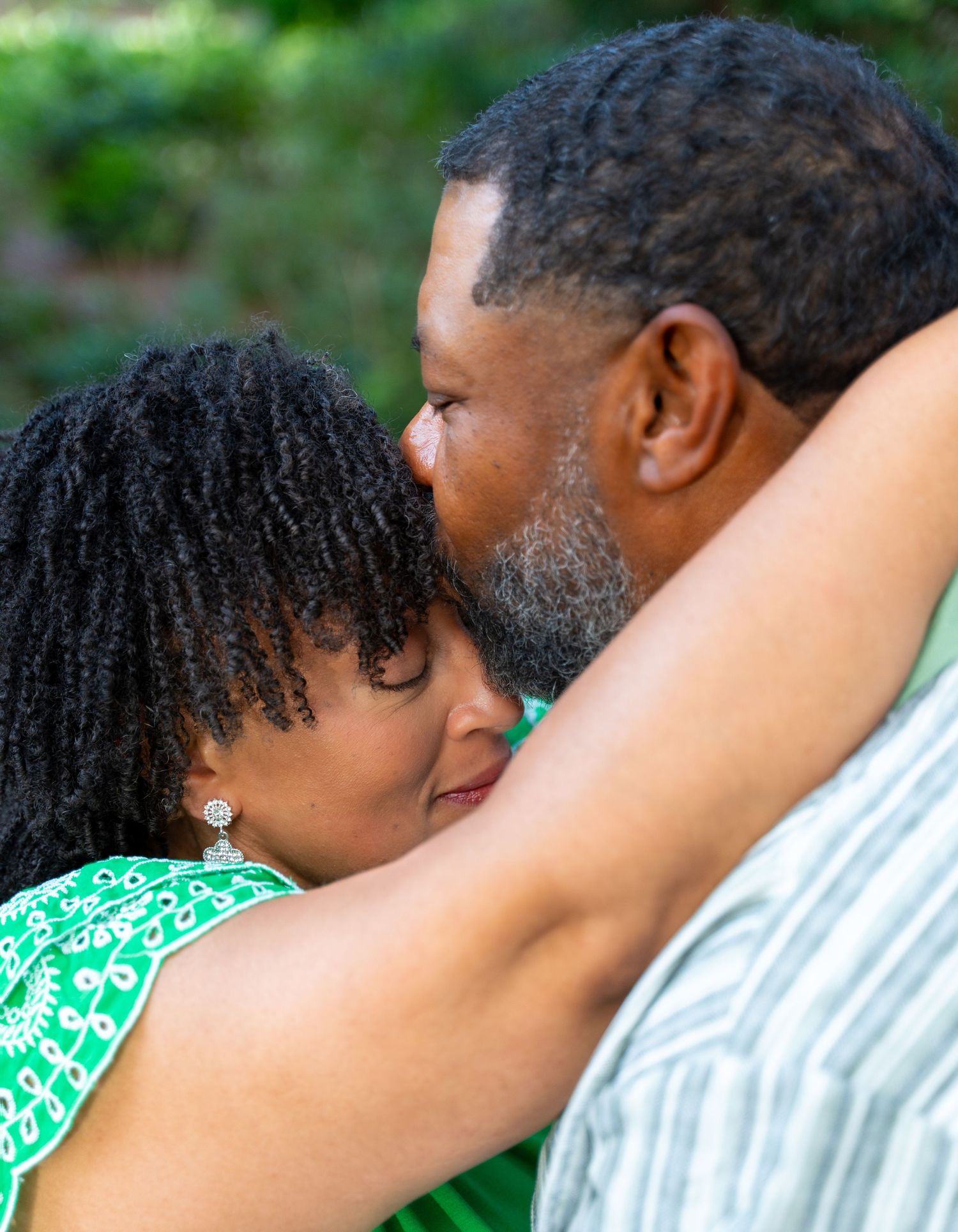 Romantic couple in green outdoor setting sharing tender moments.