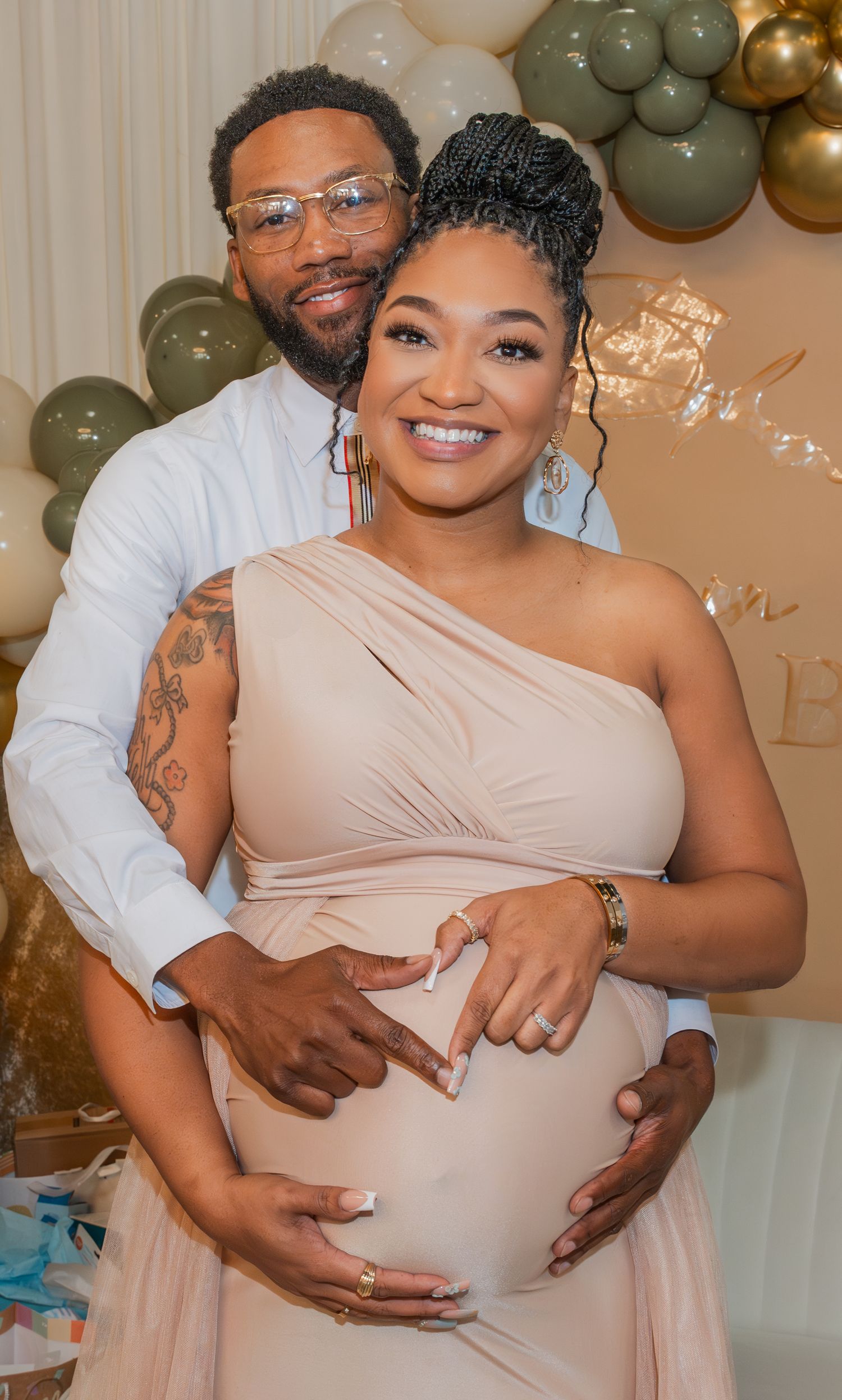 Romantic maternity photoshoot with elegant balloon decorations in warm tones.