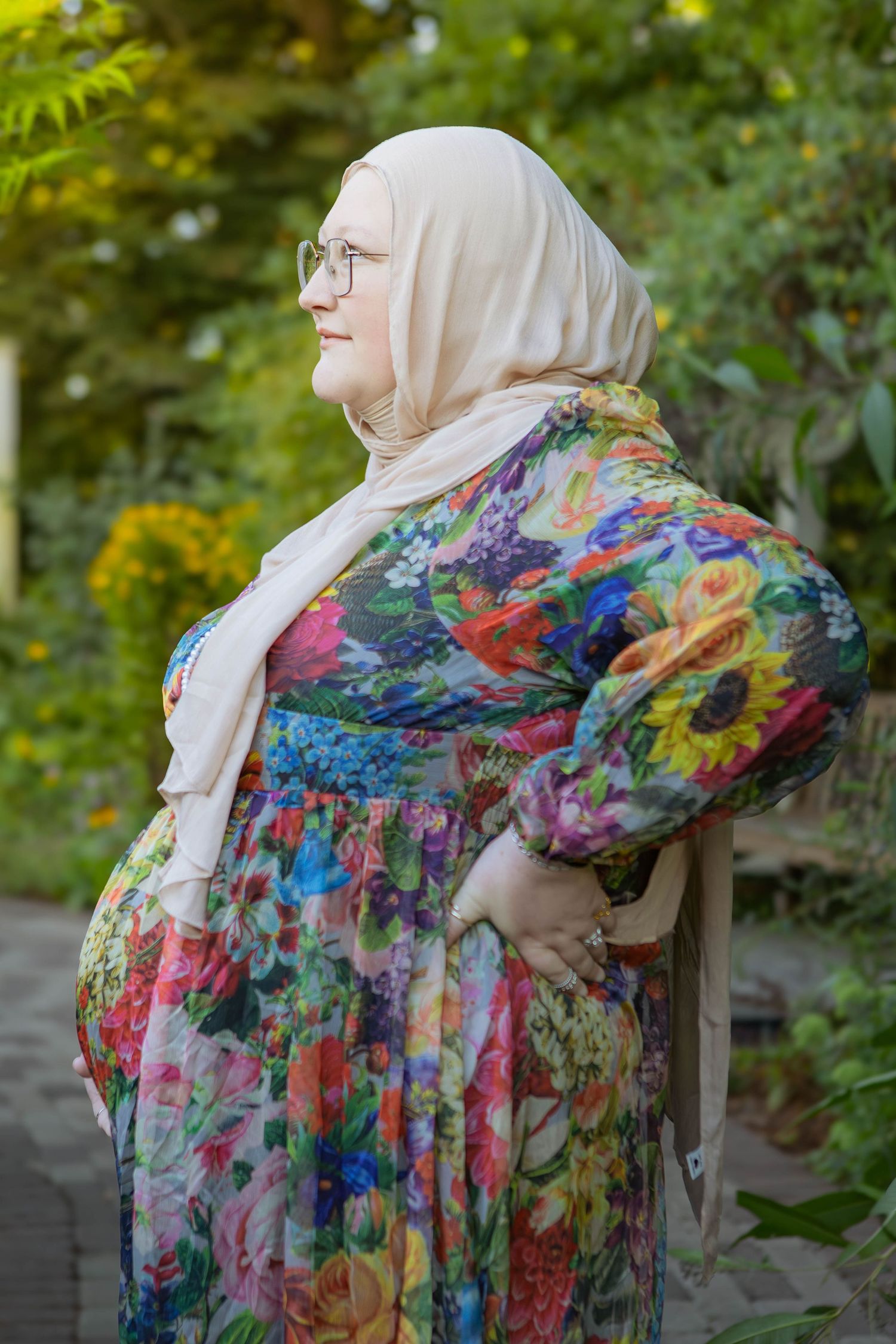 A colorful floral print dress with balloon sleeves shown in a series of outdoor maternity shots with natural greenery backdrop in Youngstown