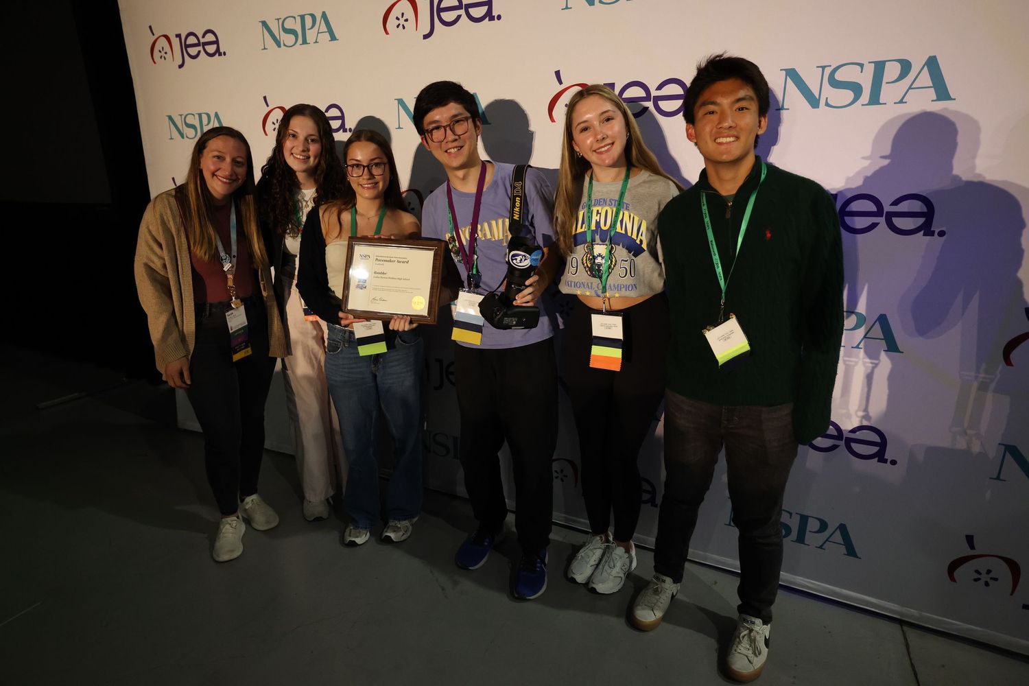 A group of students with lanyards pose together holding awards at a NSPA conference event. Luke Ye photography, Luke Ye,