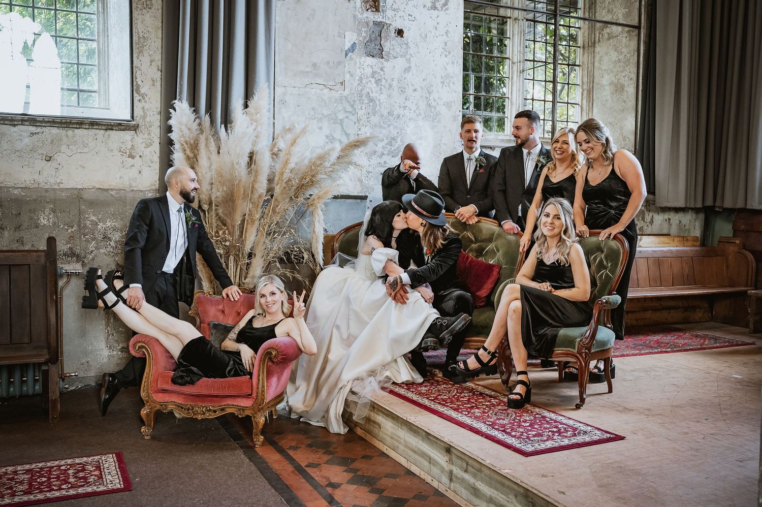 Wedding party poses playfully in a rustic church interior with pampas grass decor.