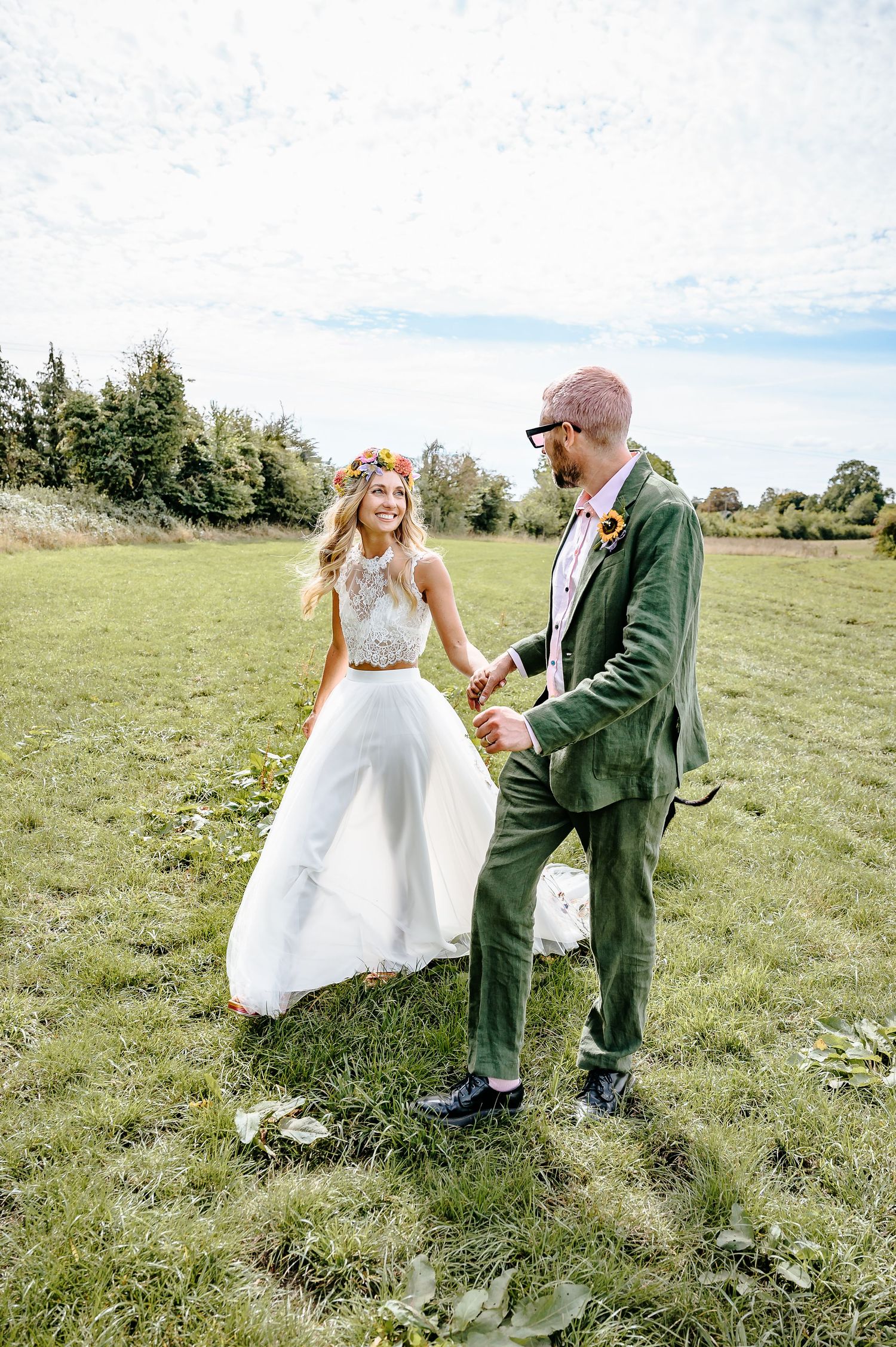 Bohemian bride in two-piece dress with floral crown dancing with groom in green velvet suit.