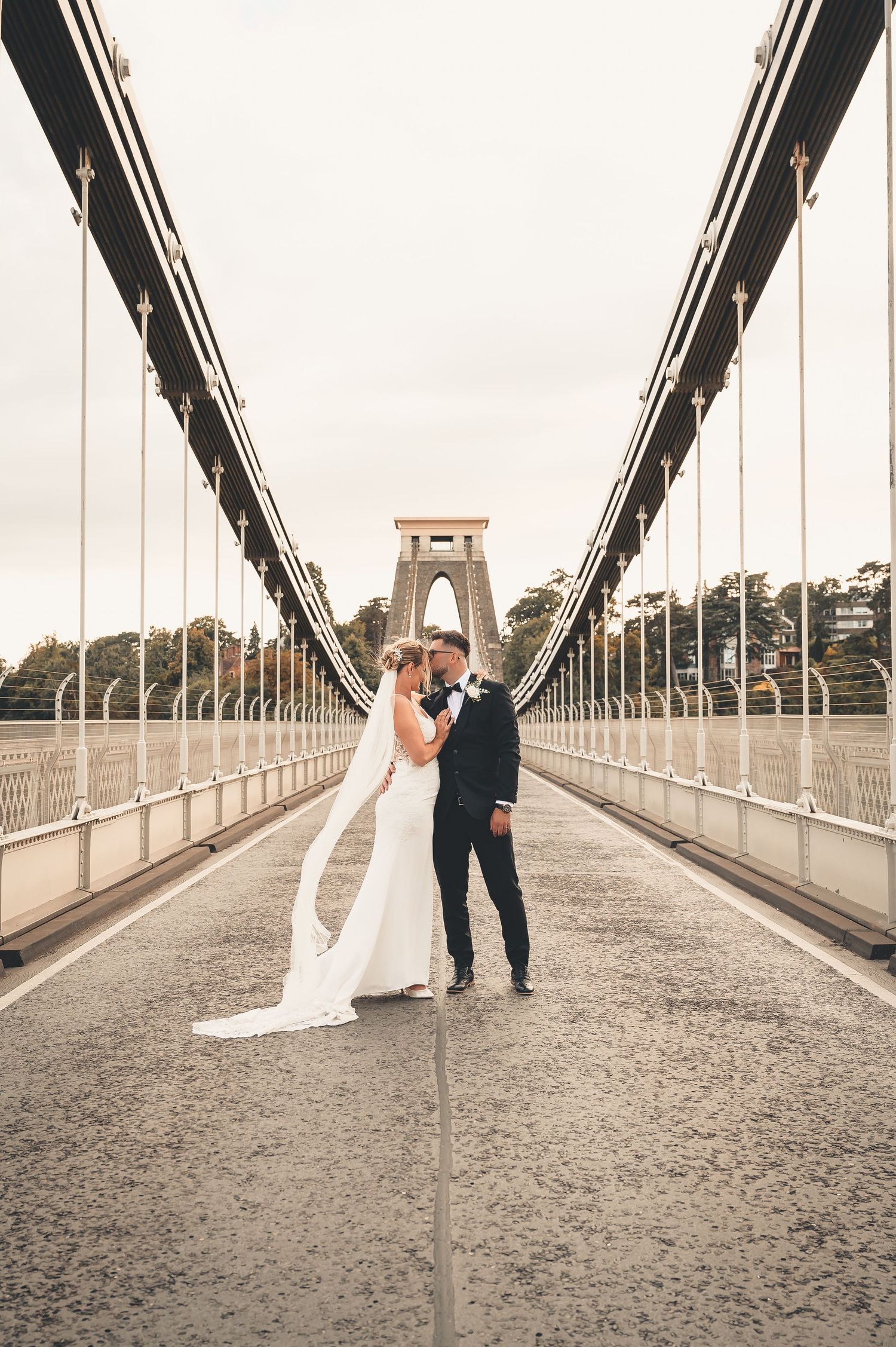 Bride and groom share a romantic moment on the Clifton Suspension Bridge, Bristol, on their wedding day.