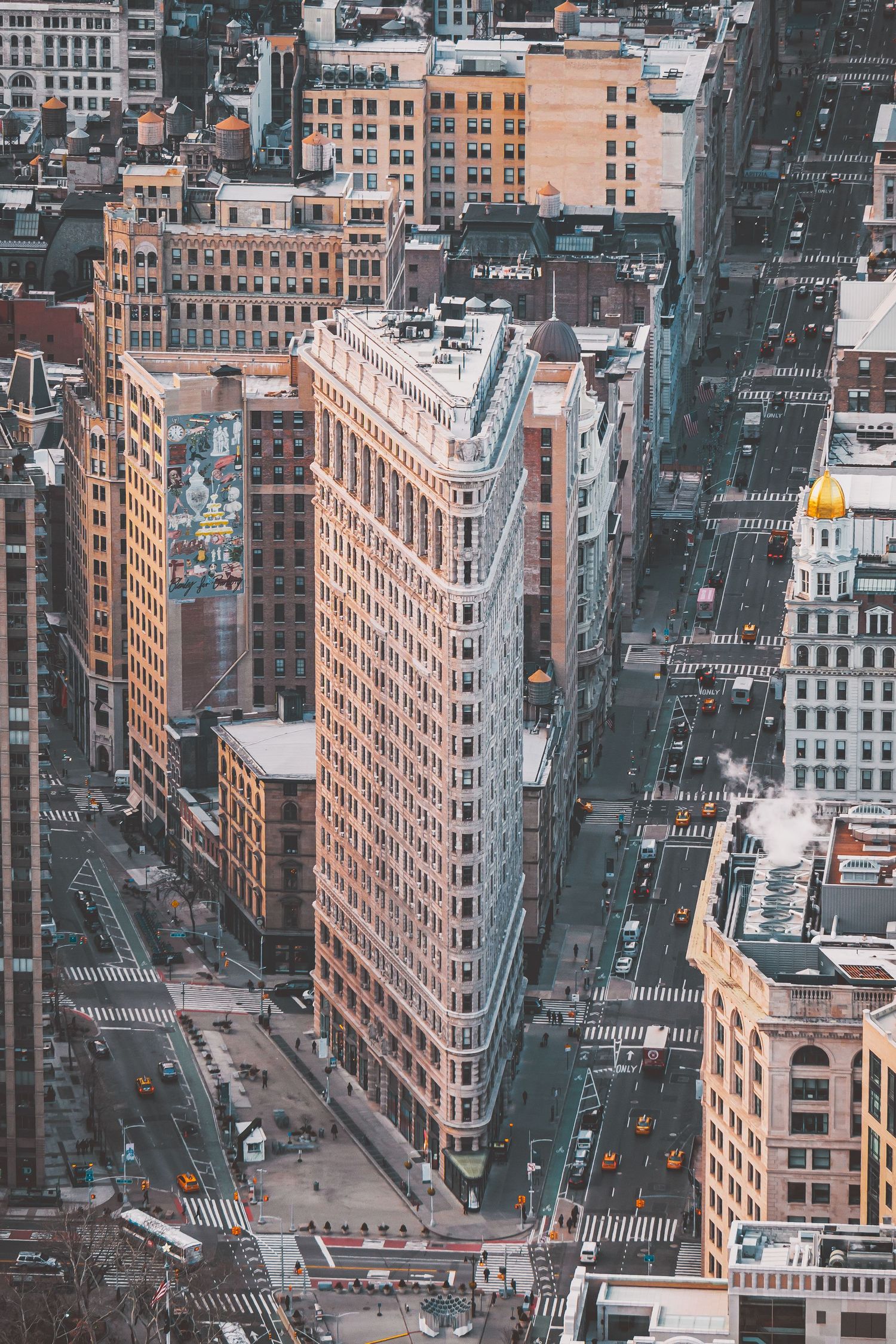 Birds-eye view of historic New York City intersection with Flatiron Building and surrounding streets.