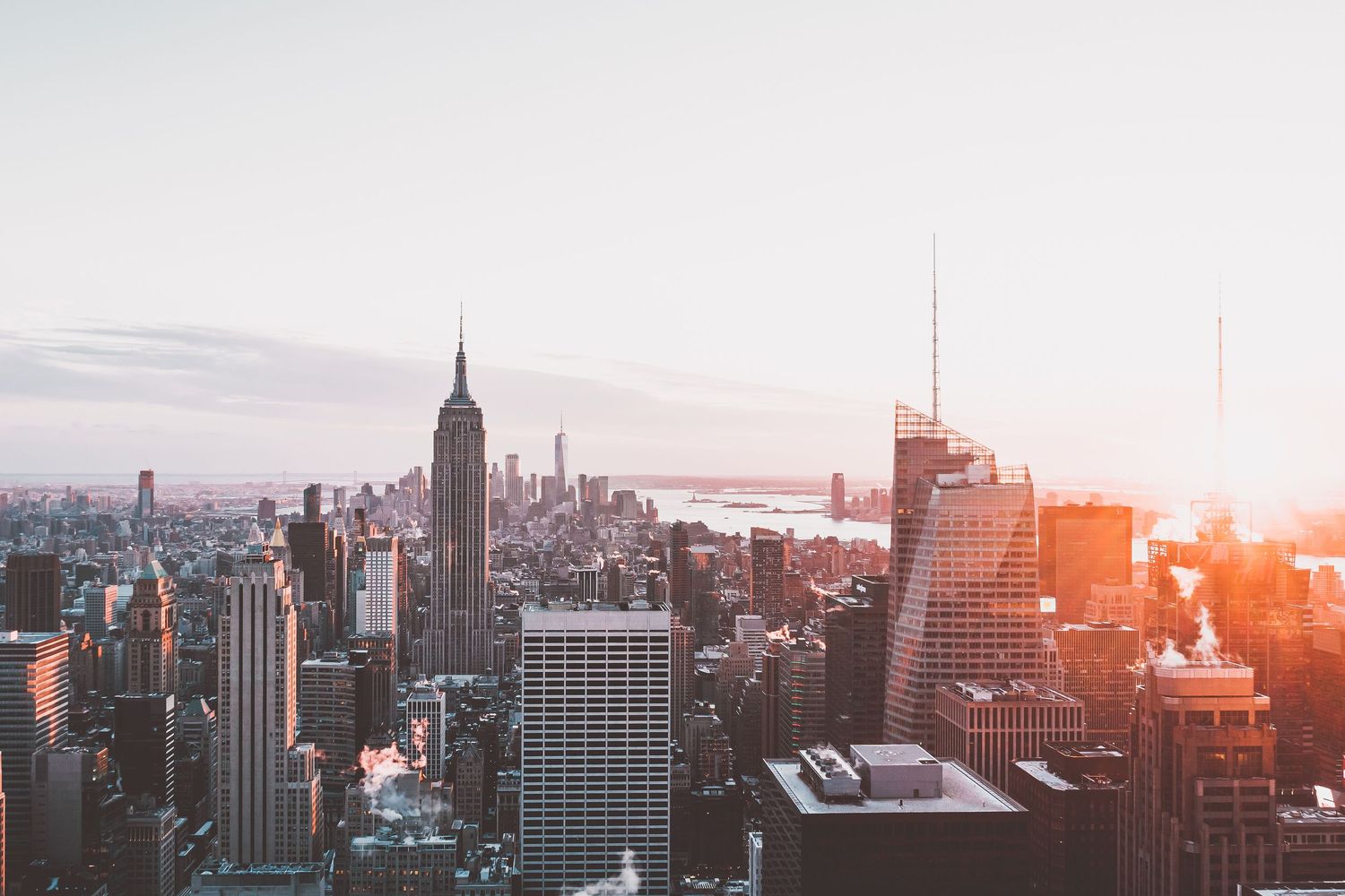 Urban cityscape of Manhattan with Empire State Building at sunset.