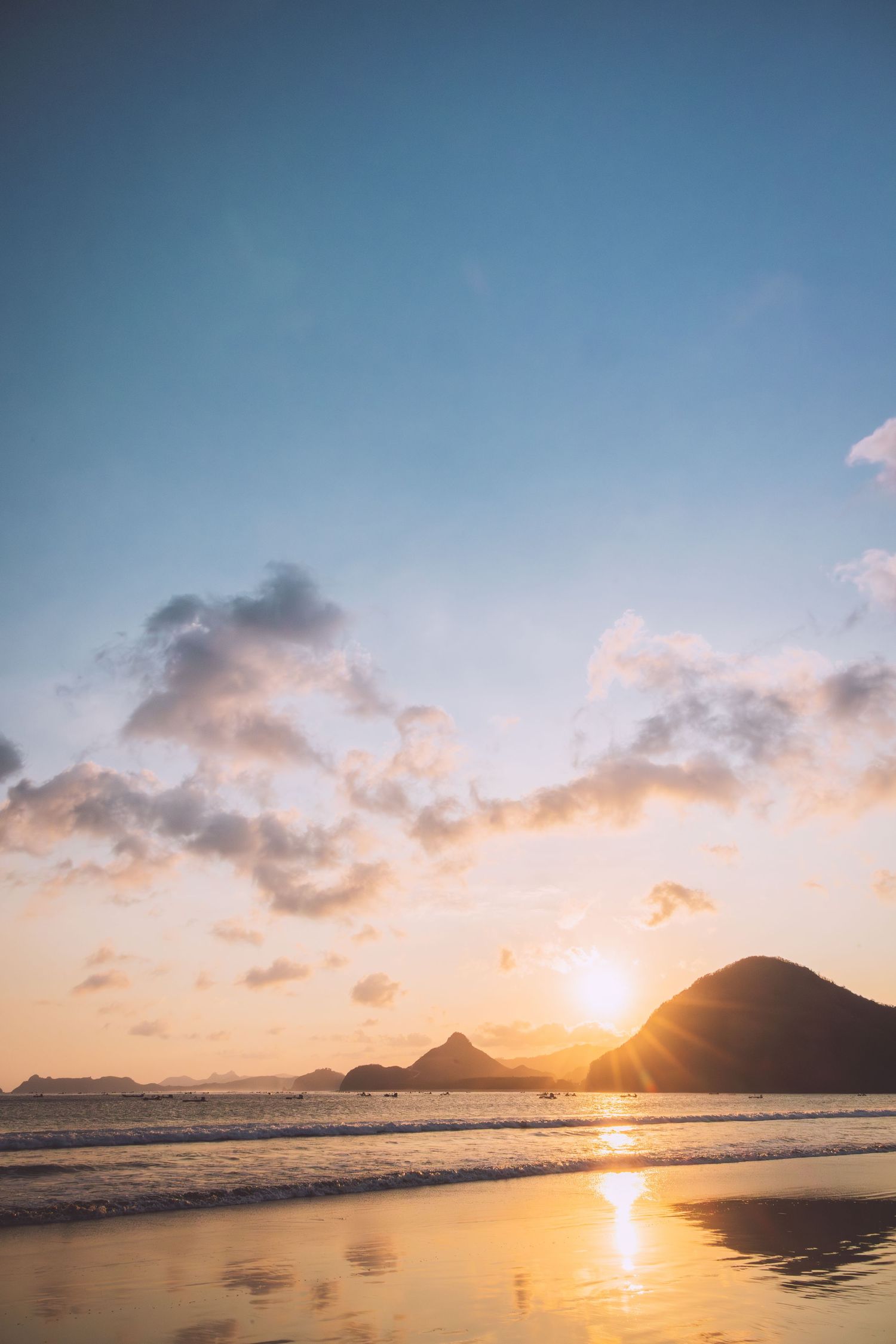 Sunset over a beach with mountain silhouettes and golden reflections on wet sand in Costa Rice.