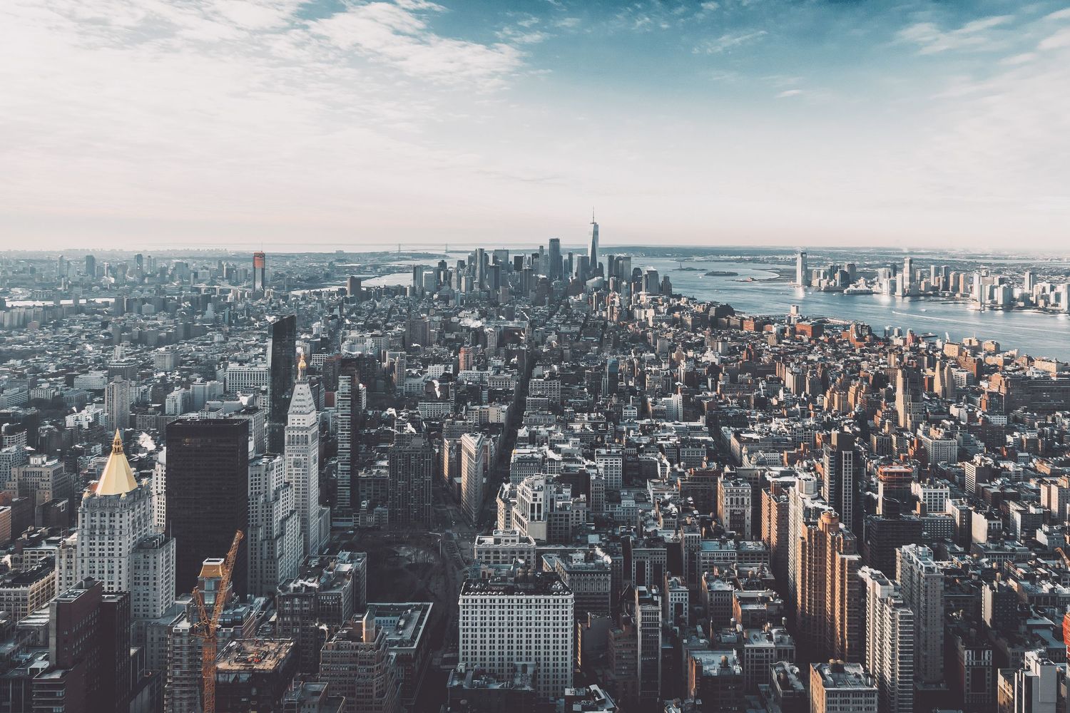 Aerial panoramic view of New York City skyline with skyscrapers against blue sky.