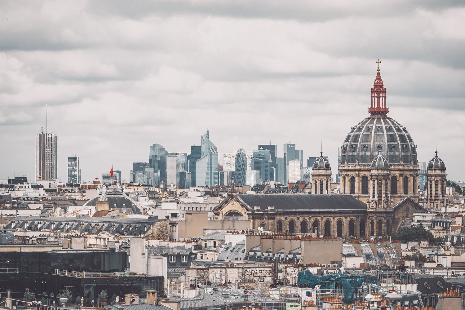Historic domes and buildings of Paris skyline under cloudy skies.