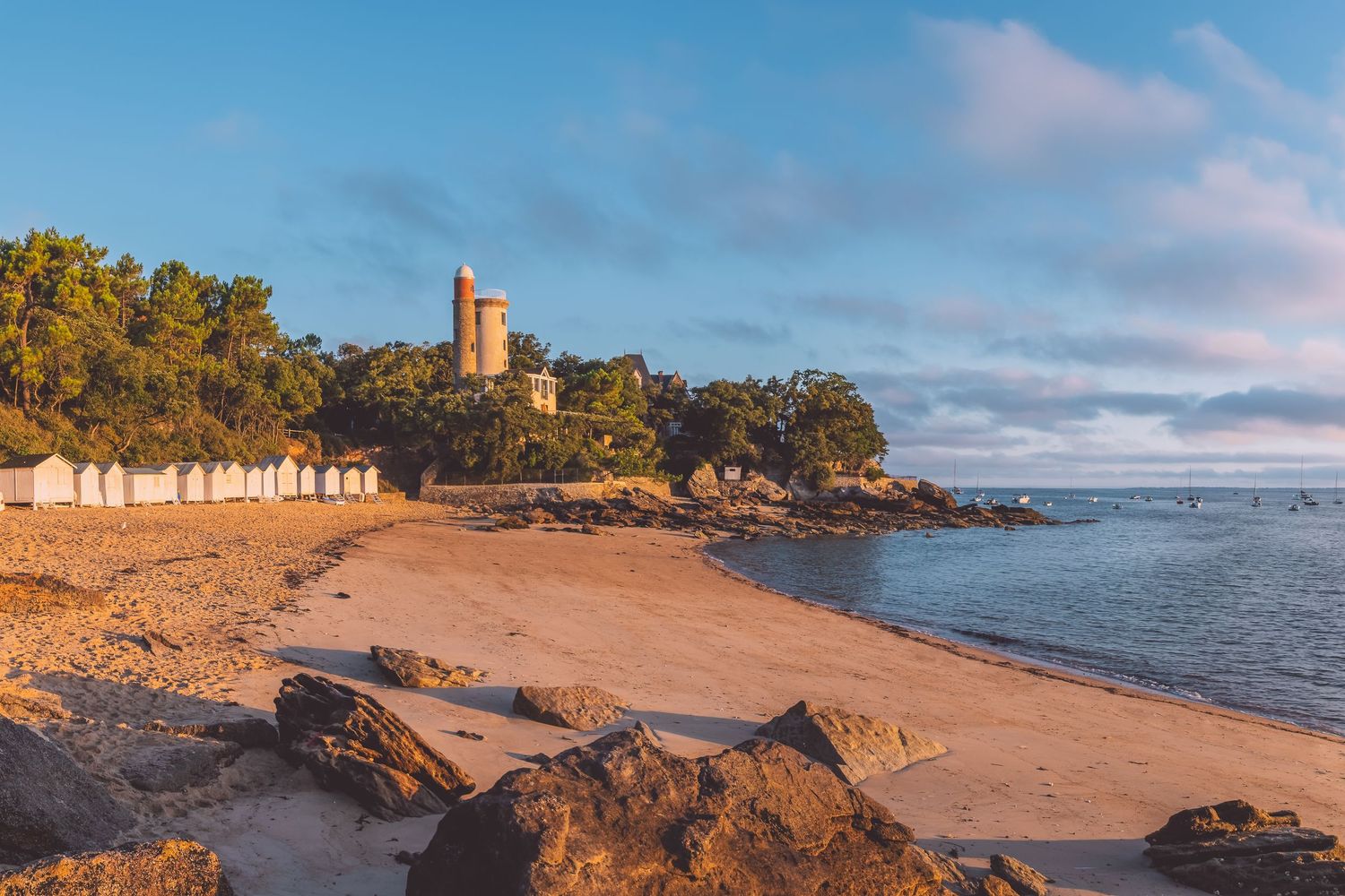 Rocky coastal landscape with sandy beach and ocean views under blue skies in Noirmoutier, France.