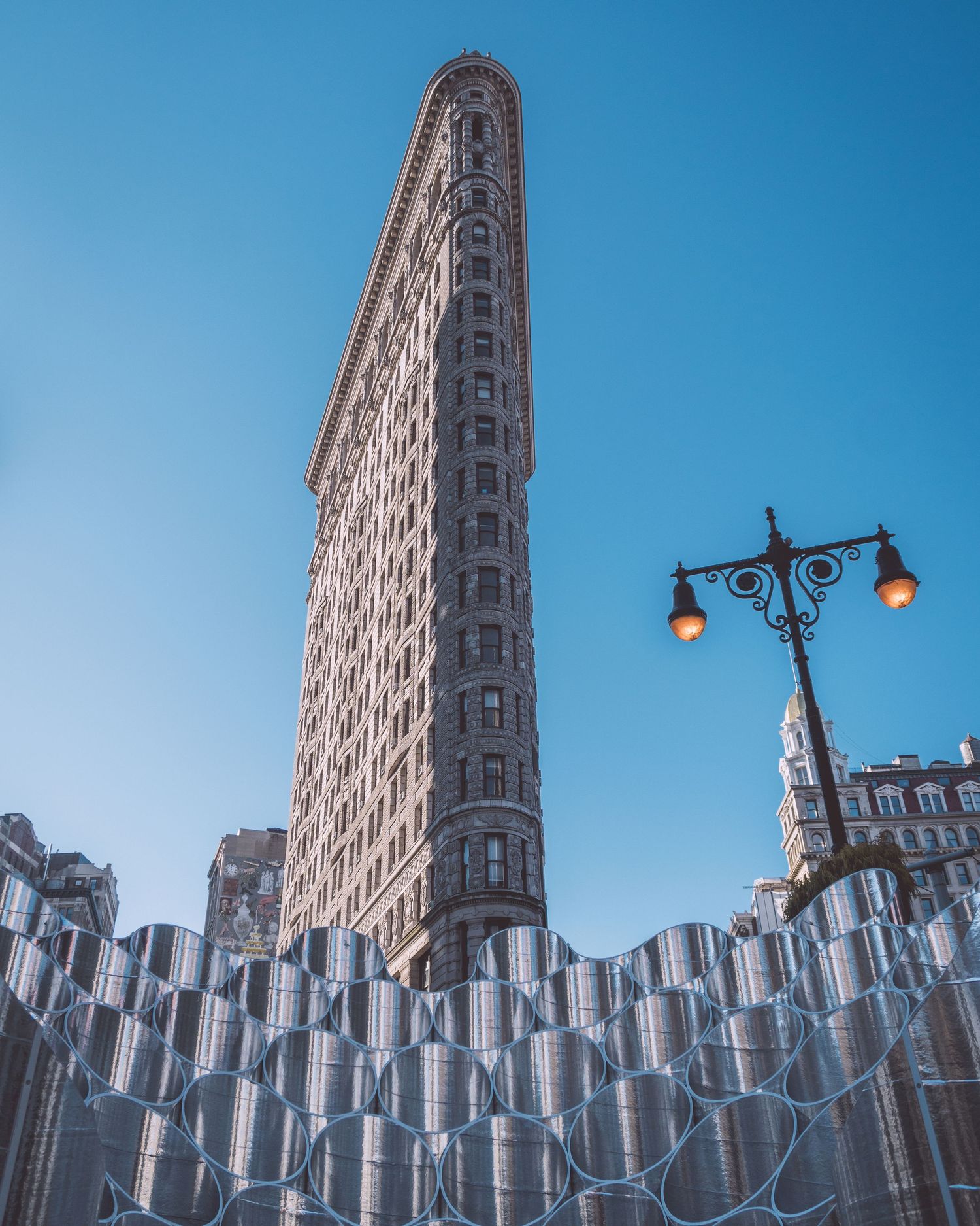 Flatiron Building in New York City against bright blue sky with decorative street lamp.