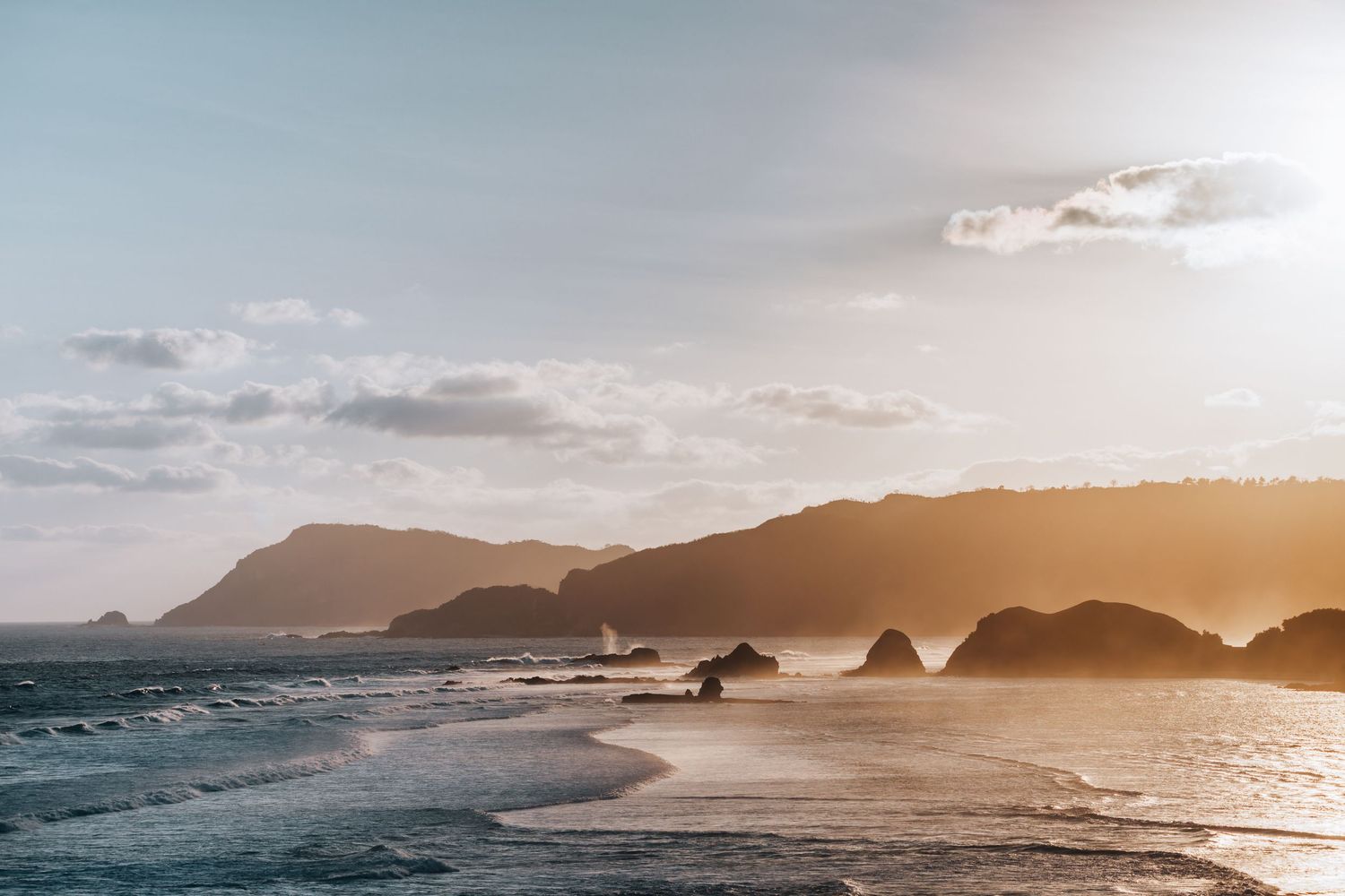 Rugged coastline with dramatic cliffs and rock formations at sunset along the ocean shore in Lombok, Indonesia.